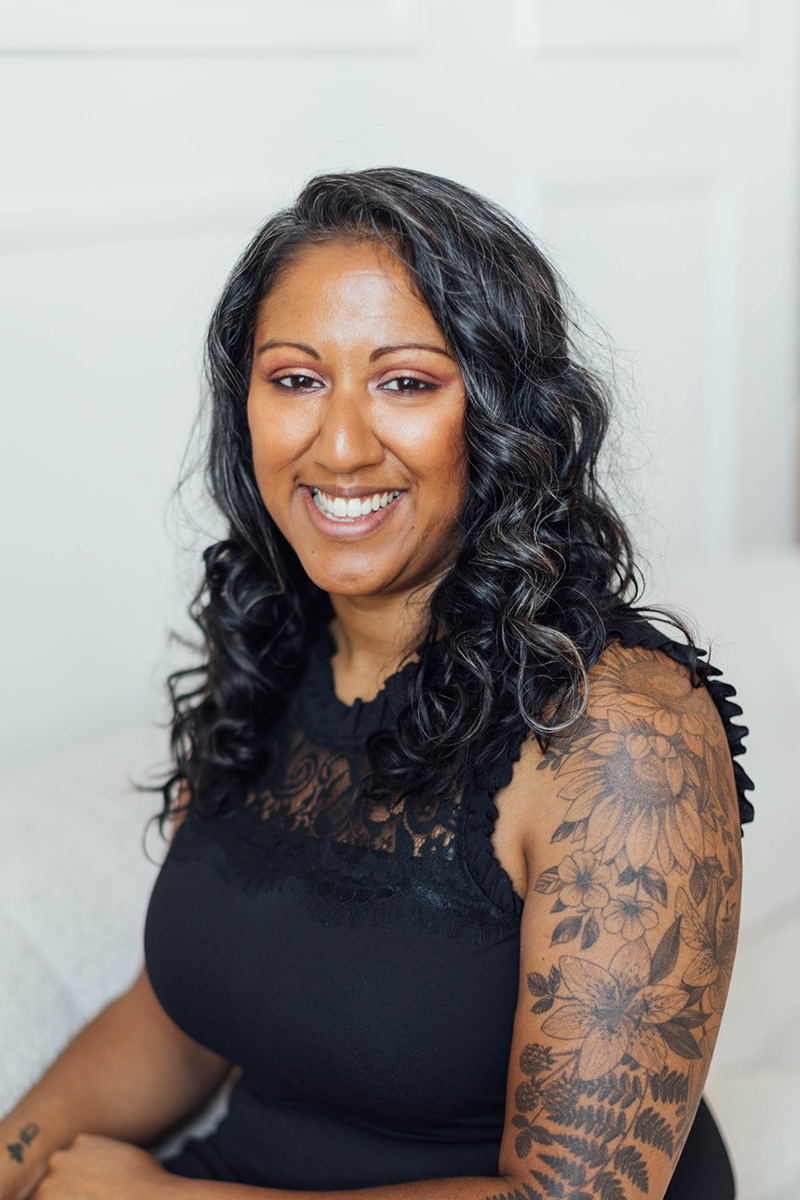 Thameena Nazir, wearing a black sleeveless top with lace details, showing a floral tattoo on her left arm.