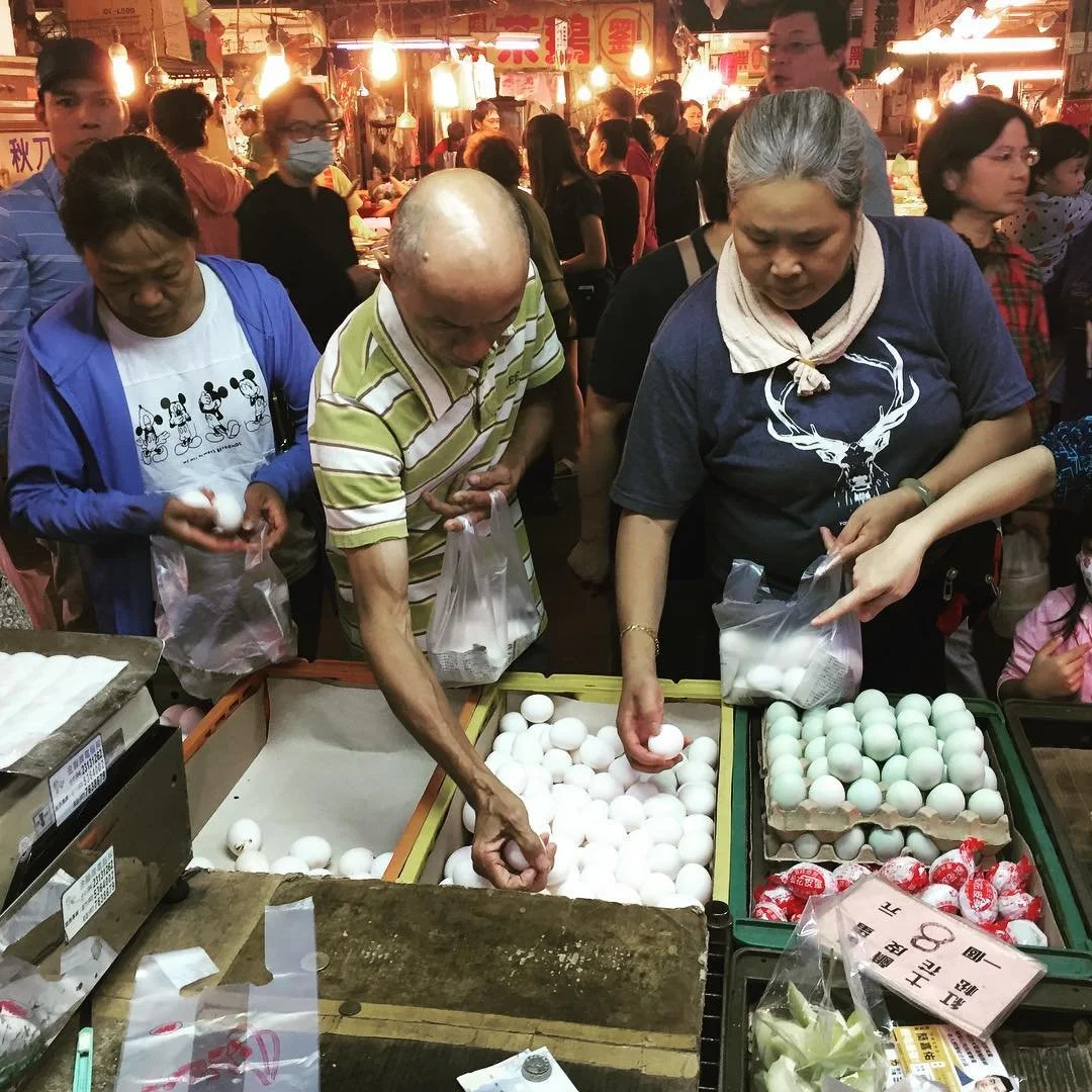 Local Taiwanese purchase fresh farm eggs from a night market in Taichung during a Tricia Pomering Cultural Experience in Taiwan.