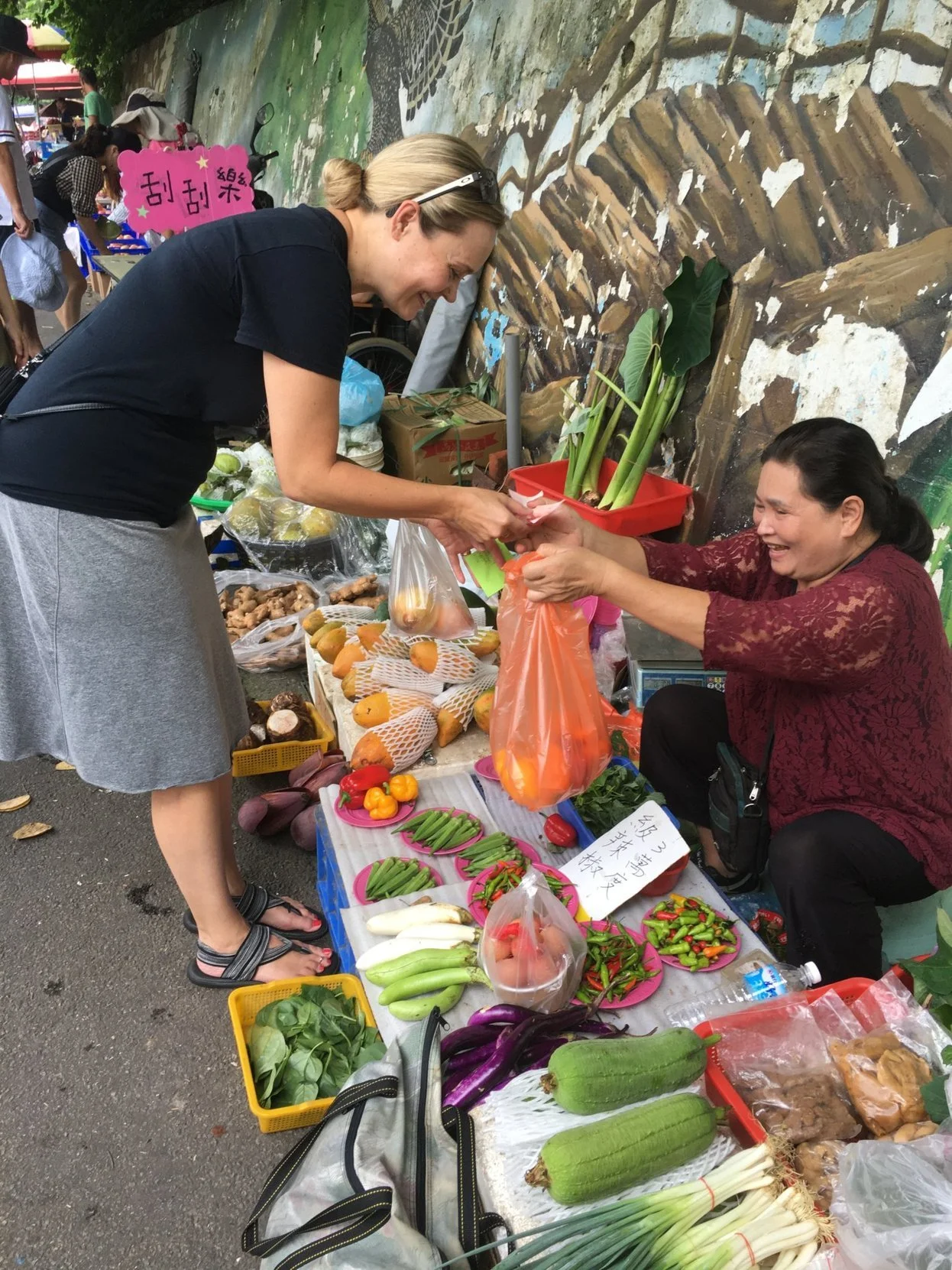 A woman purchases fresh product from an open air market stall in Taichung during a Tricia Pomering Cultural Experience in Taiwan.