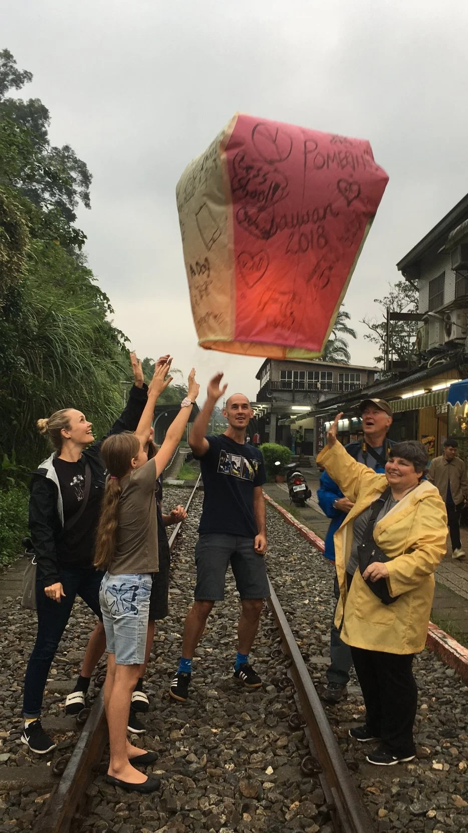 A group of people release a large sky lantern into the the air in Pingxi, Taiwan during a Tricia Pomering Cultural Experience.