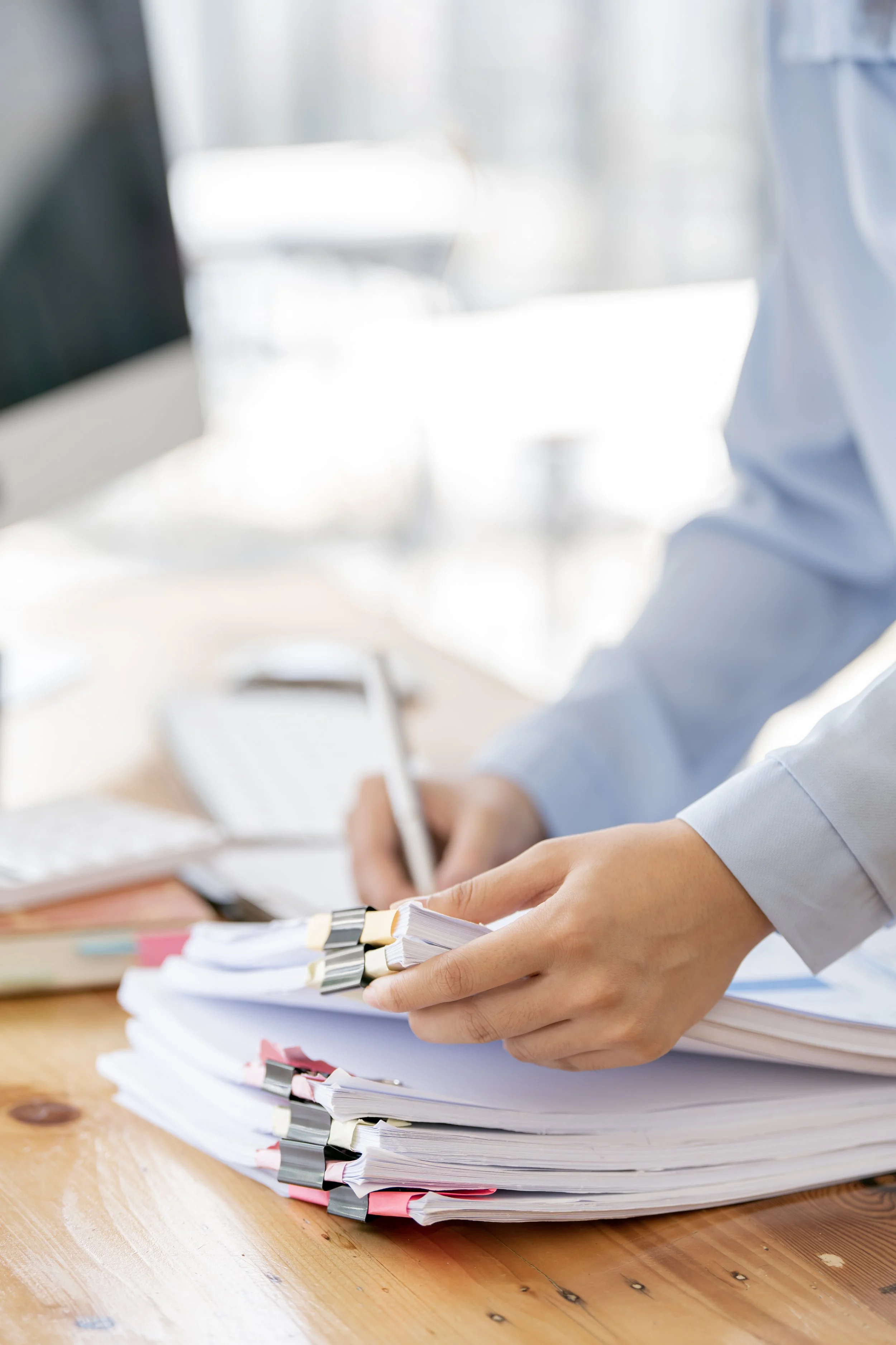 Business women sifting through a stack of paper at her desk