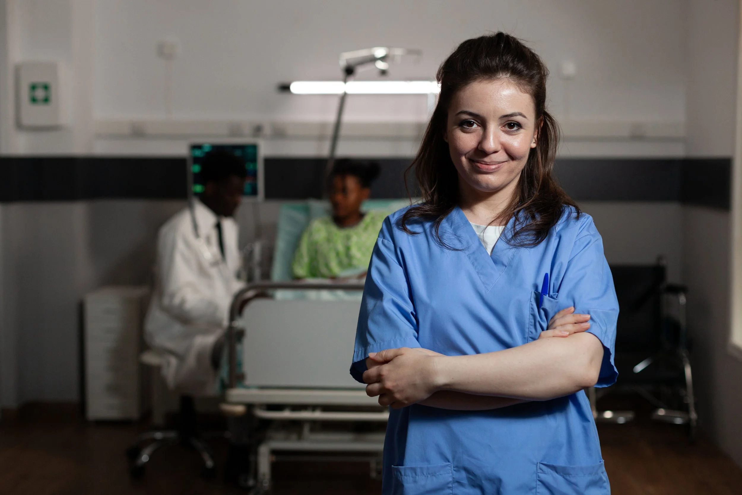 Nurse standing in ER room with her arms crossed smiling at the camera.