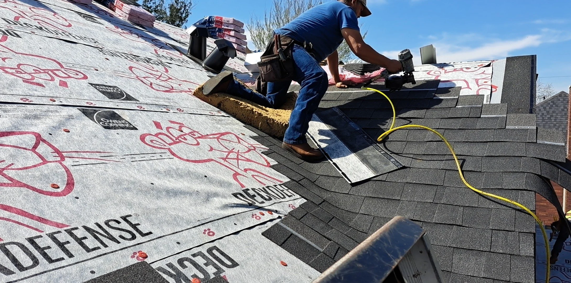 Construction worker installing roof shingles on a house