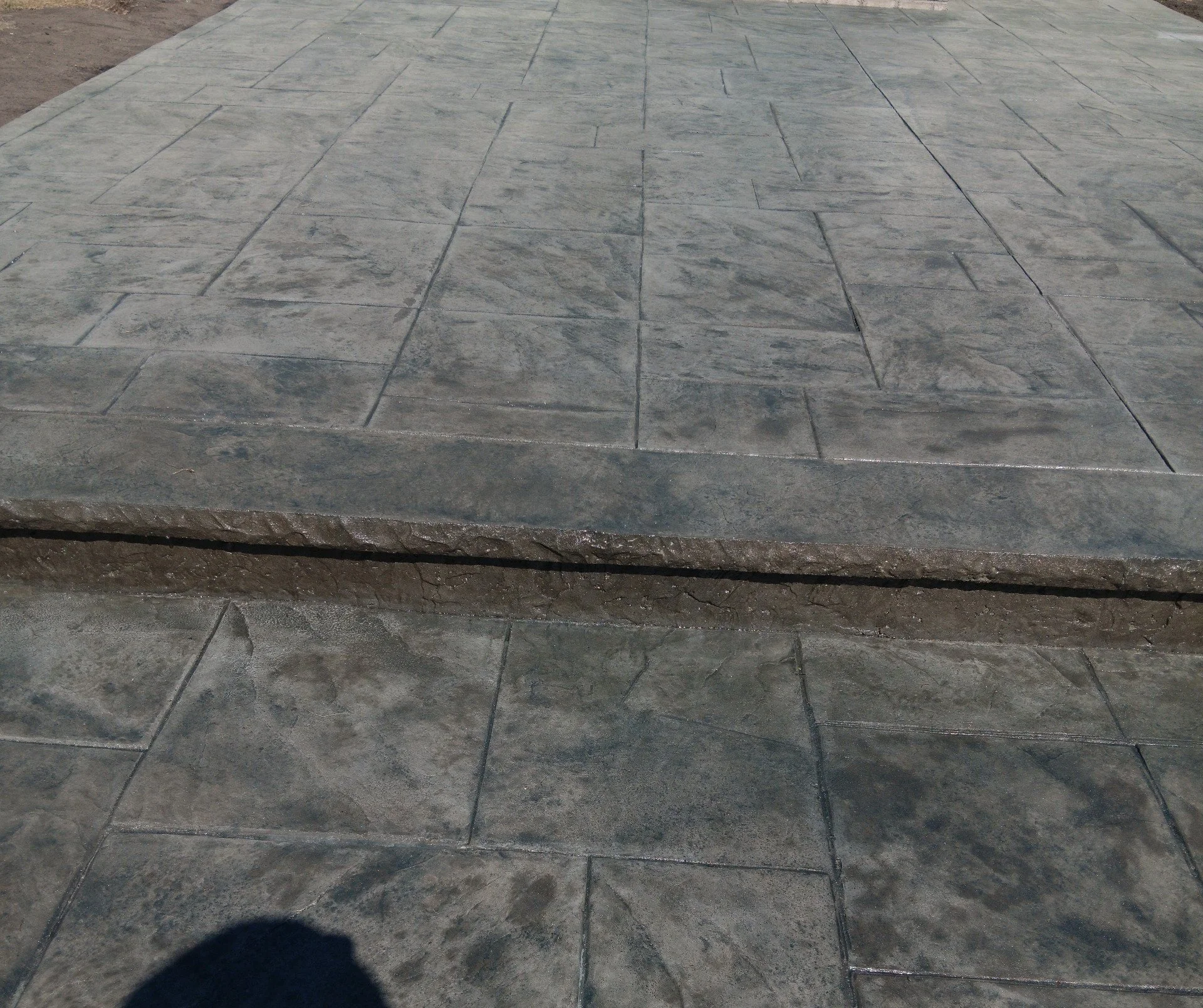 Close-up of a stone step and paved ground with large, rectangular stone tiles.