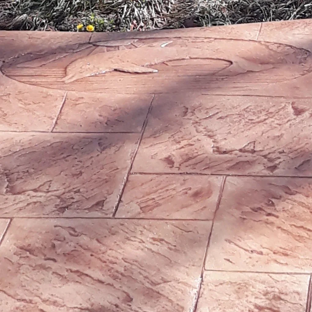 Close-up of a sandstone-tiled surface with irregularly shaped patterns and shadows cast across it.