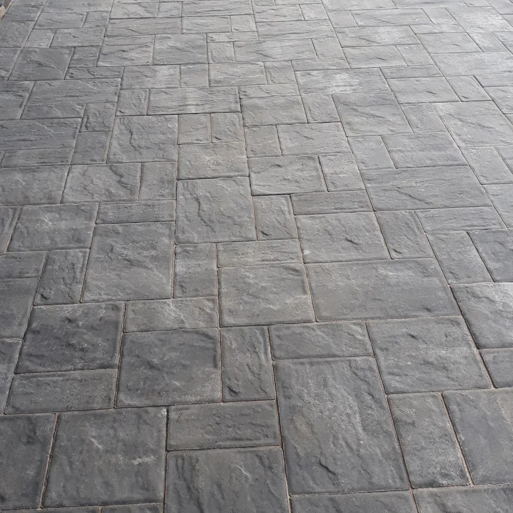 Gray stone paver patio with a textured surface and a pattern of rectangular and square stones.