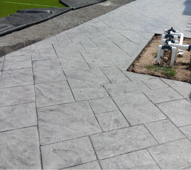 Newly installed concrete sidewalk with landscape piping system on the side.