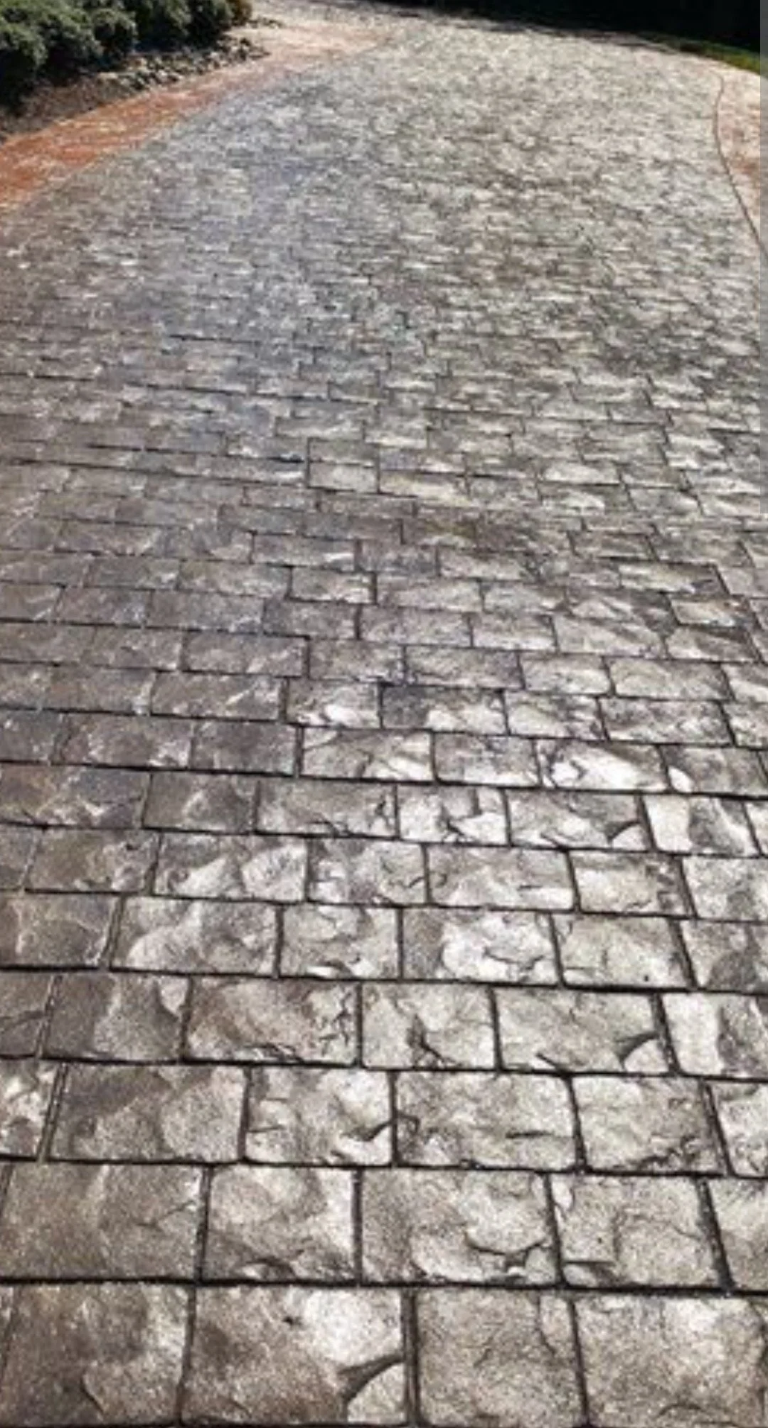 A cobblestone driveway or path with an arched design in the background.