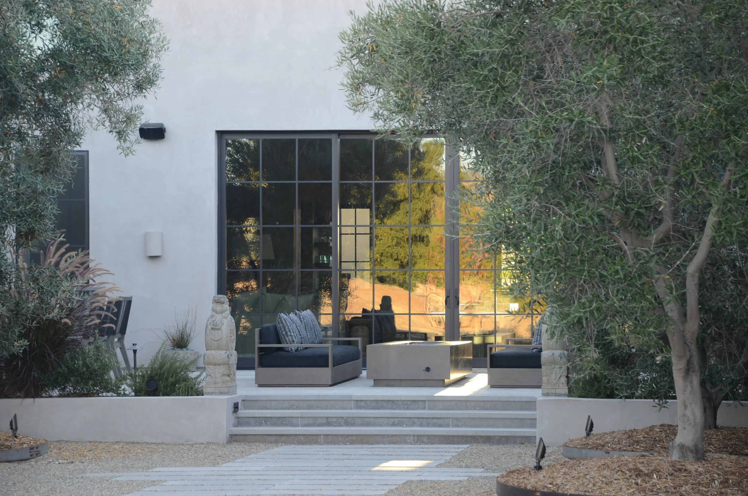 Modern patio with glass doors, outdoor seating, and trees