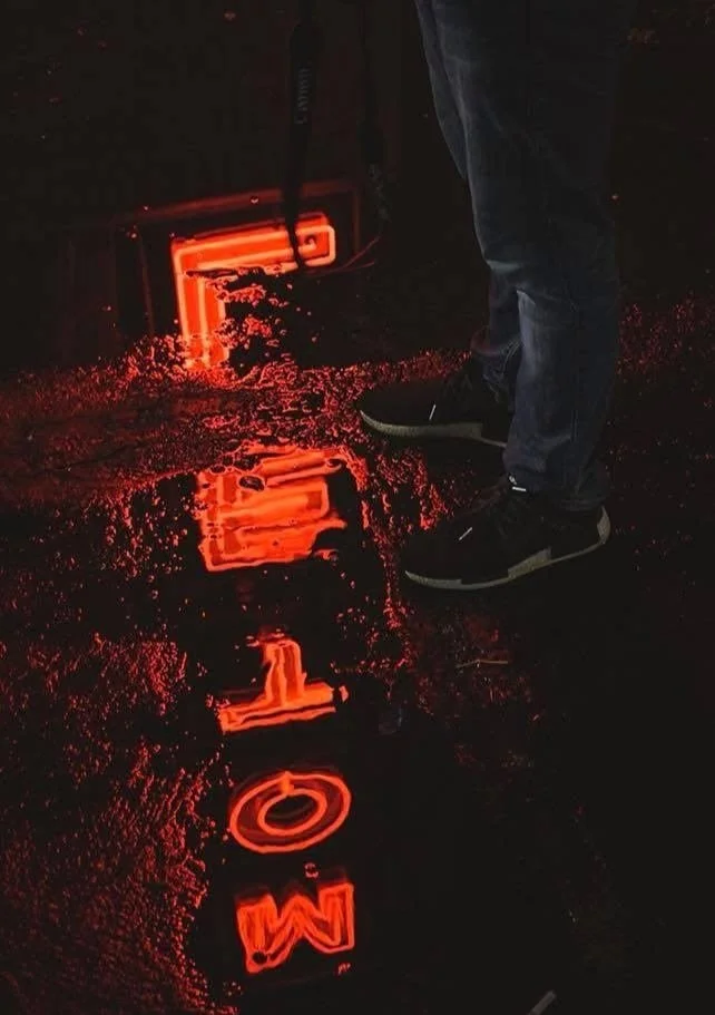 Neon sign reflected in a puddle at night