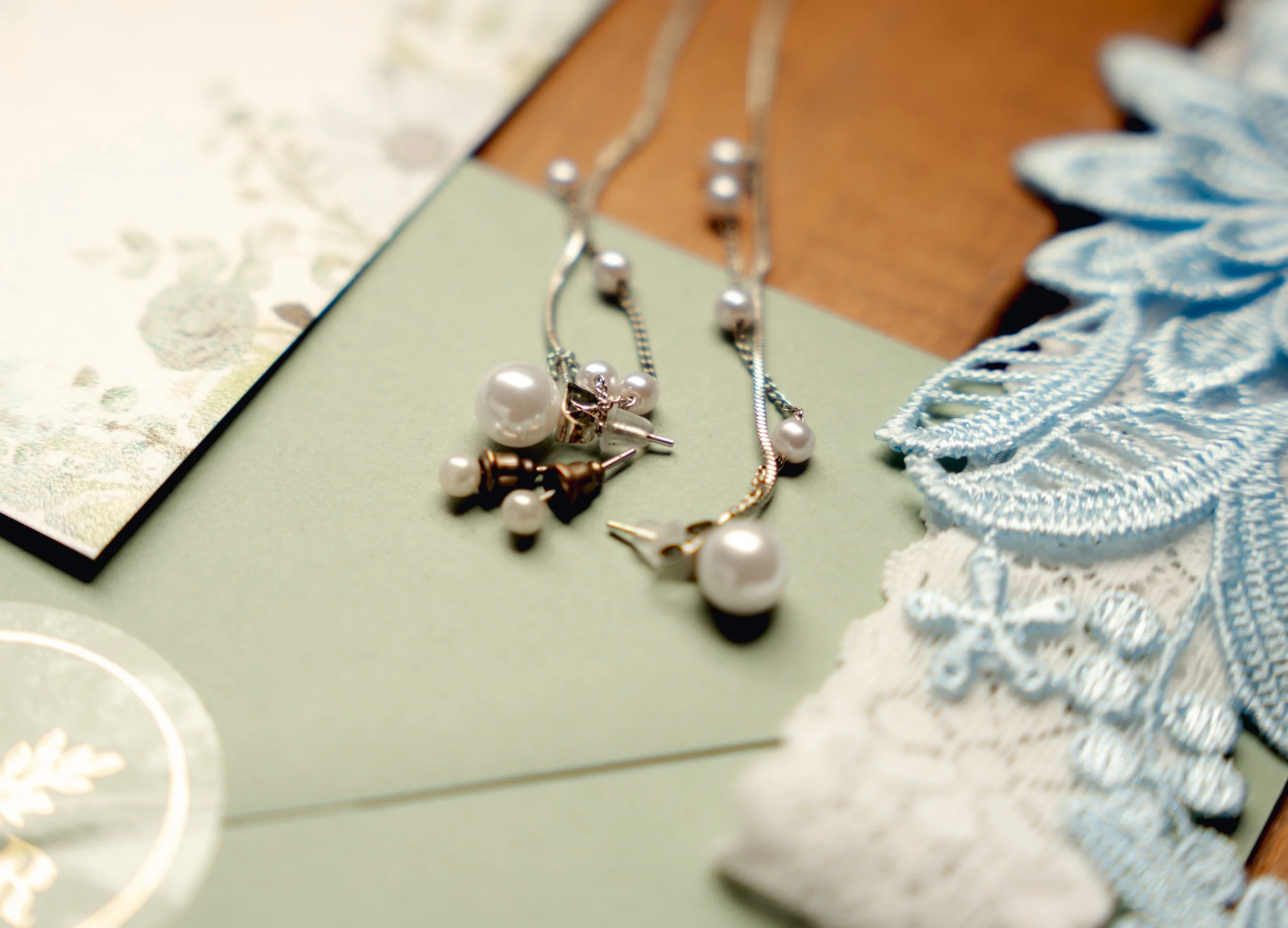 Close-up of pearl jewelry including necklaces and earrings on a vintage background with lace and paper