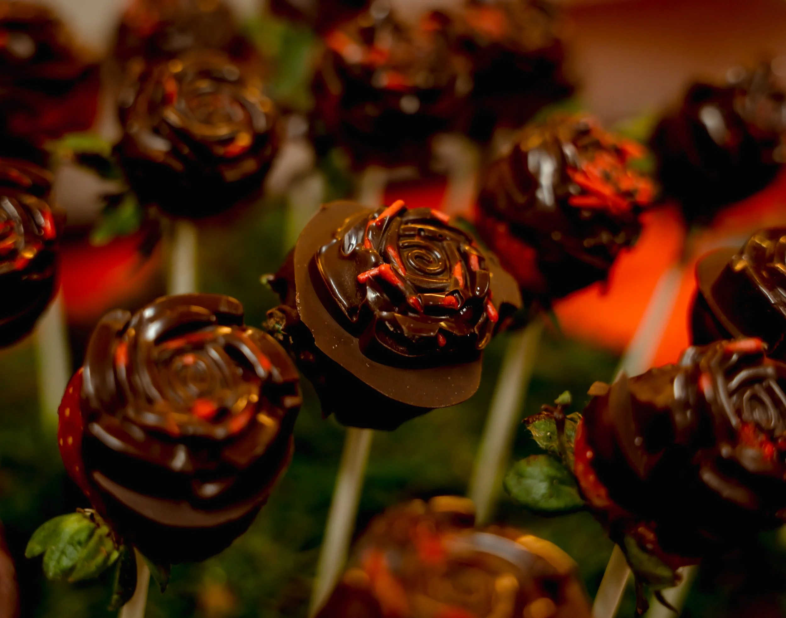 Chocolate-covered strawberries shaped like roses on sticks.