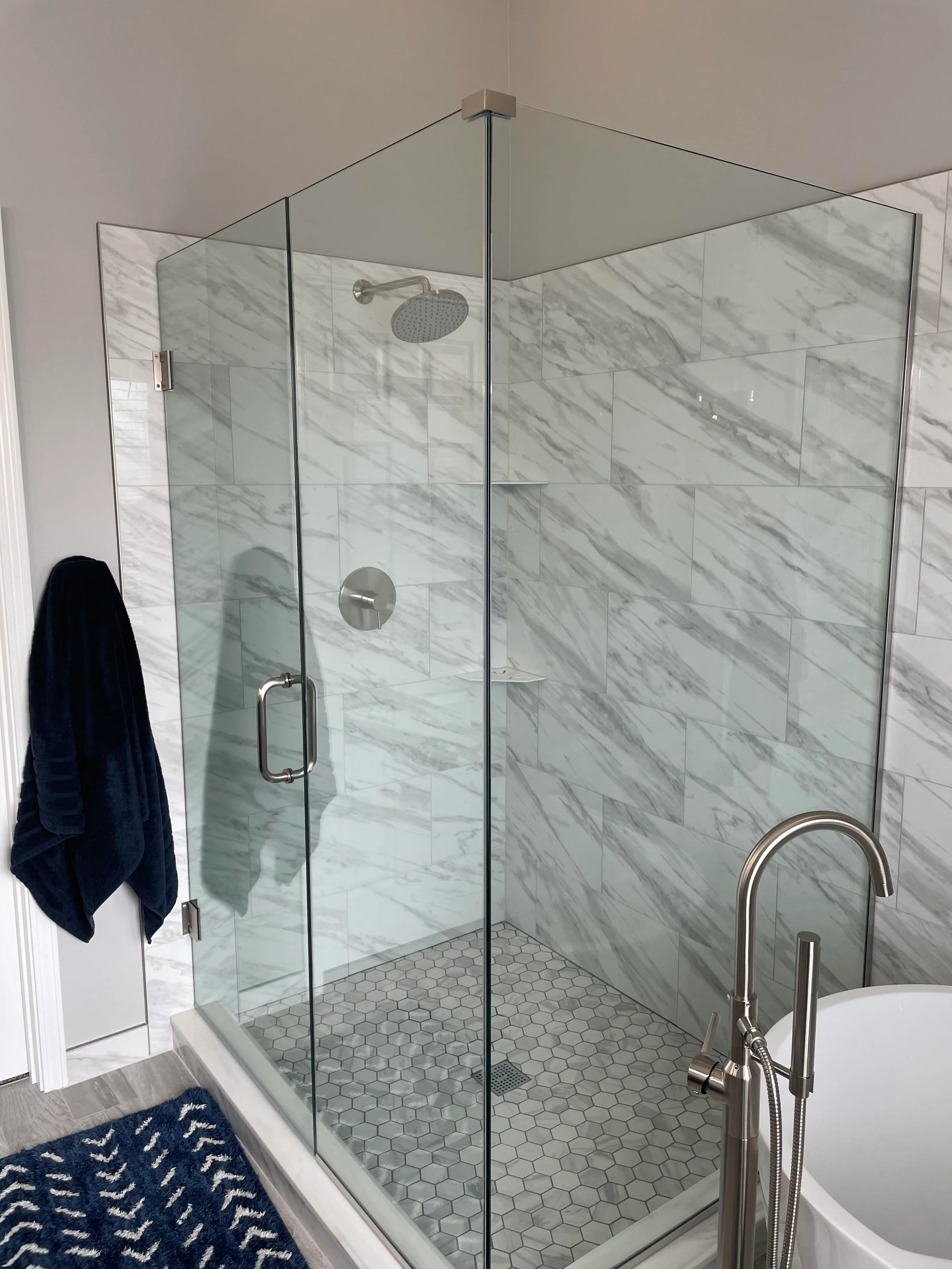 Walk-in shower remodel with frameless glass, built-in bench, linear drain and marble hex mosaic floor in La Cañada, California