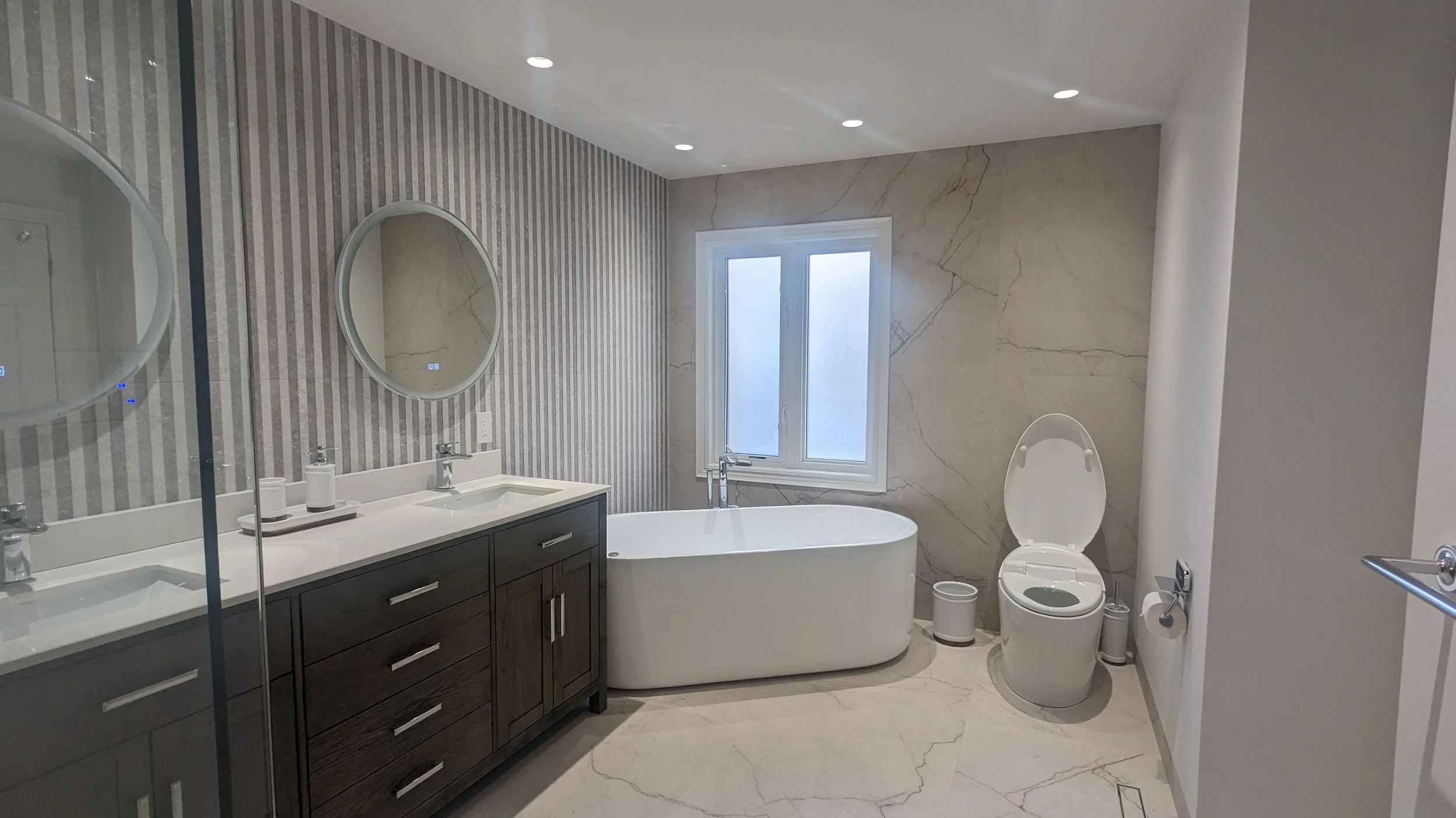 Corner shower remodel with frameless glass enclosure, marble-look porcelain walls and freestanding tub in La Cañada, California
