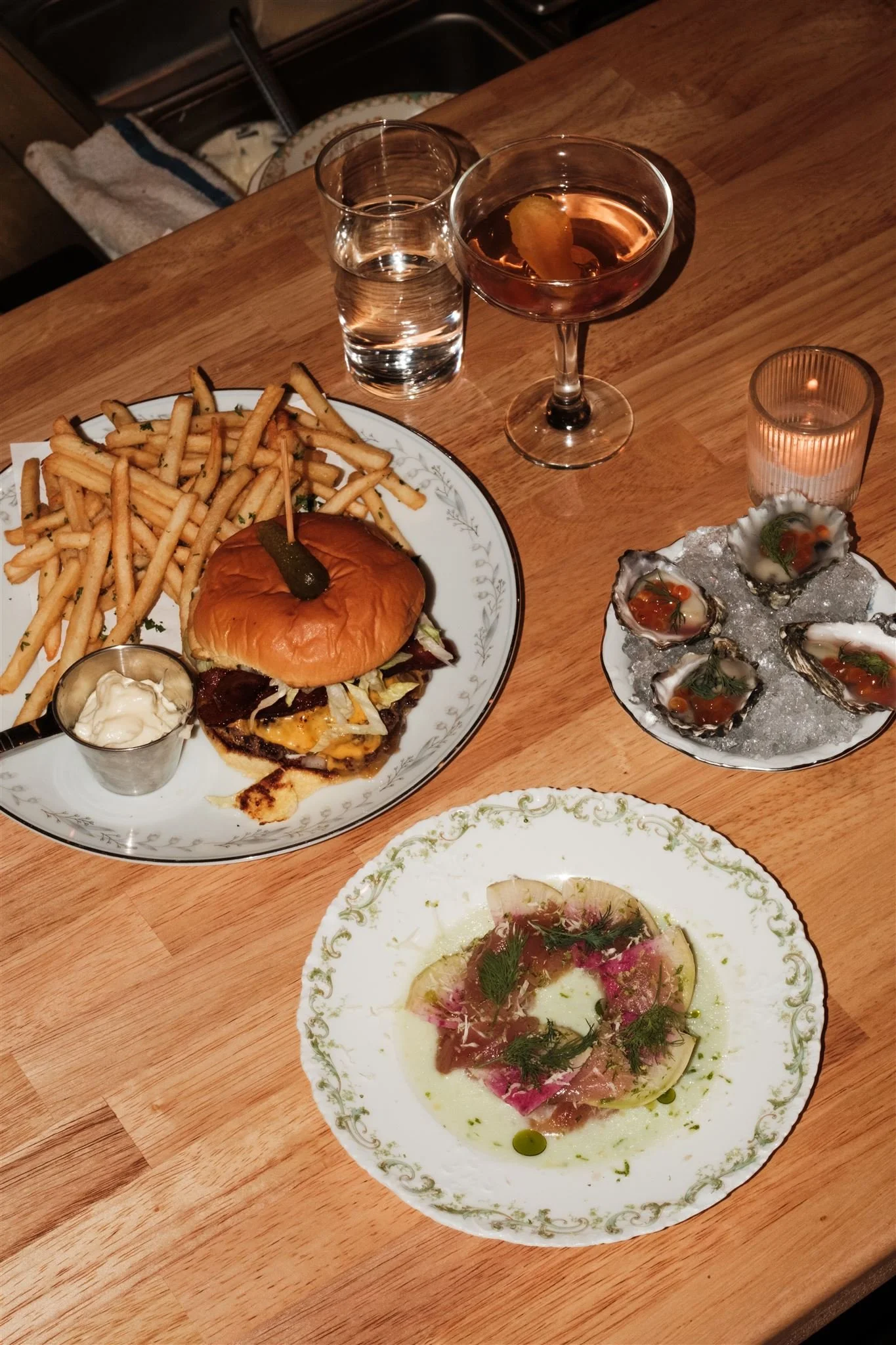 Table of food at Roe a downtown Bellingham Restaurant with a burger and fries and cocktail