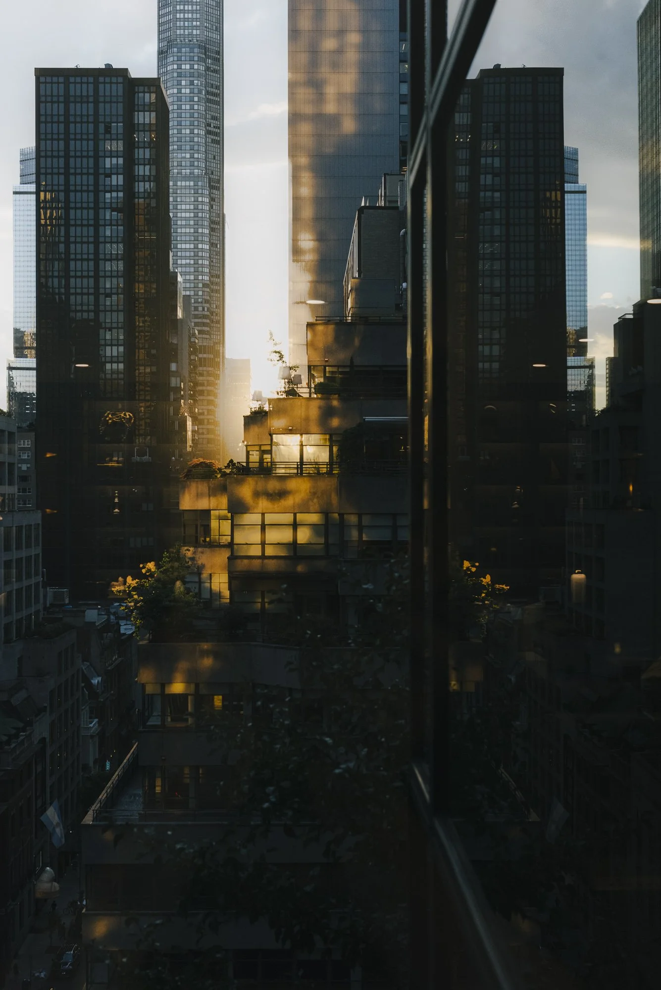 City skyline at sunset with tall modern buildings, reflected on a glass window, creating a mirror image of the cityscape.