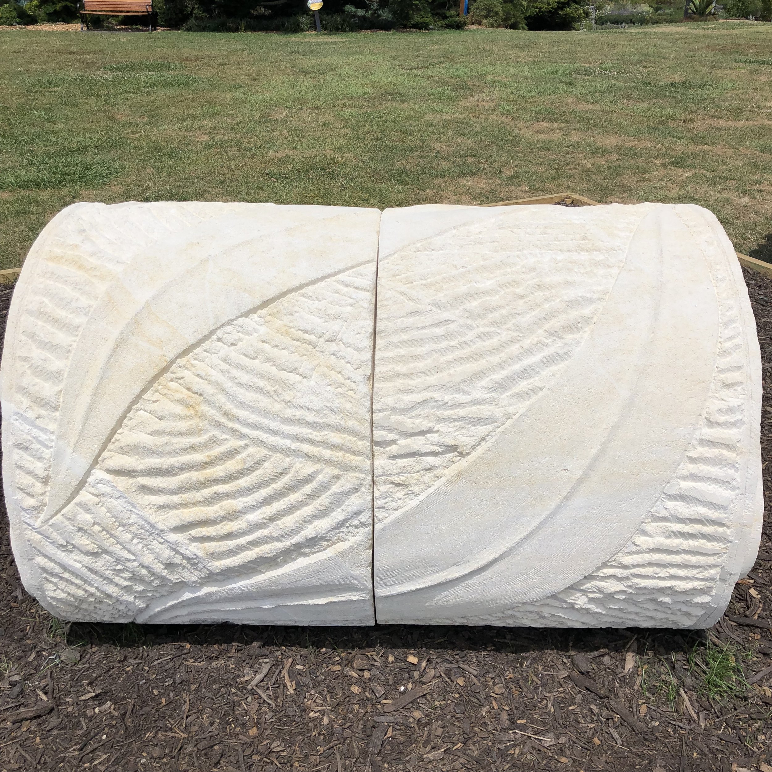 Large stone sculpture with abstract patterns on grass