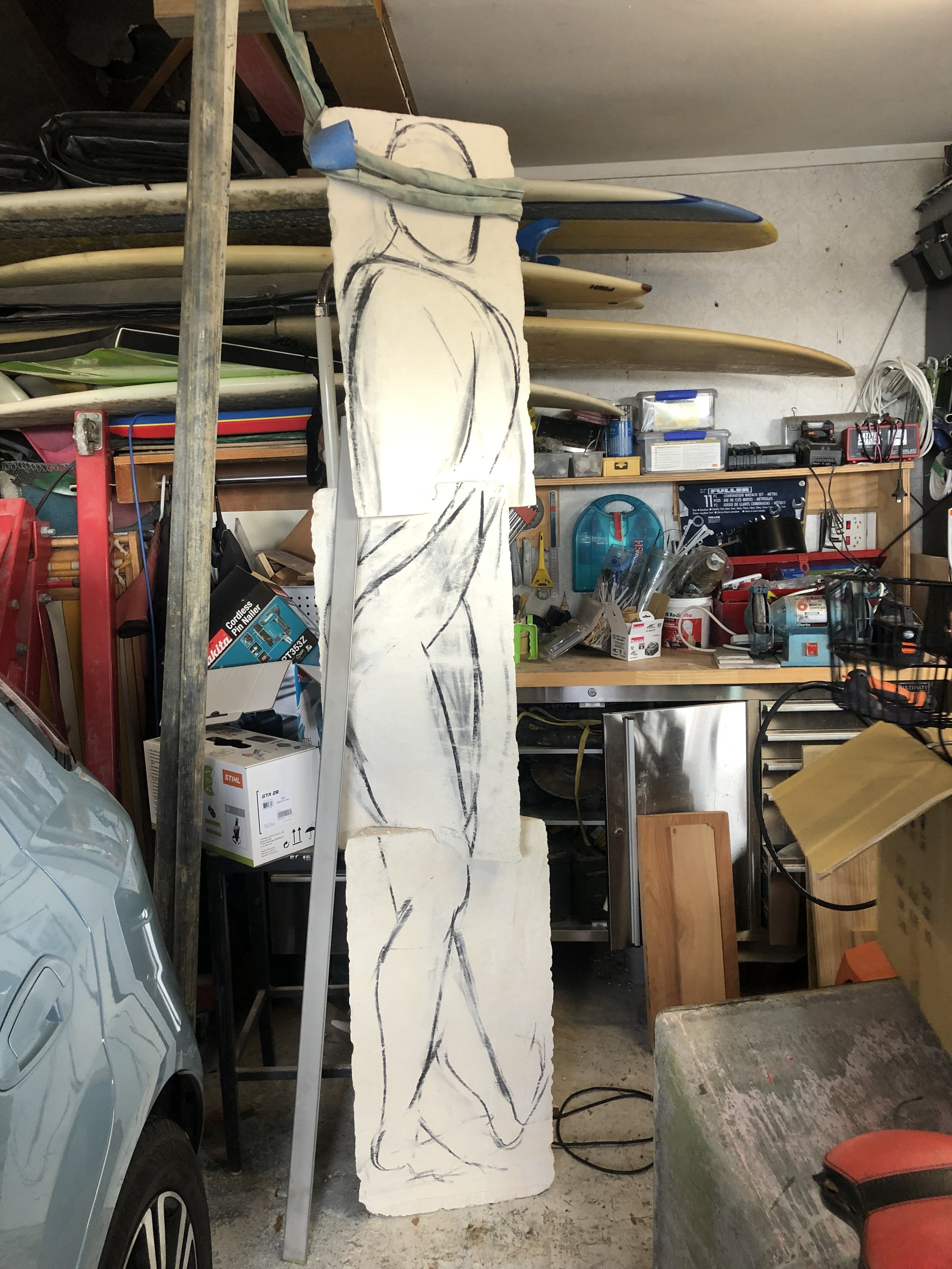 Garage with surfboards, drawing on foam board, car, and various tools.