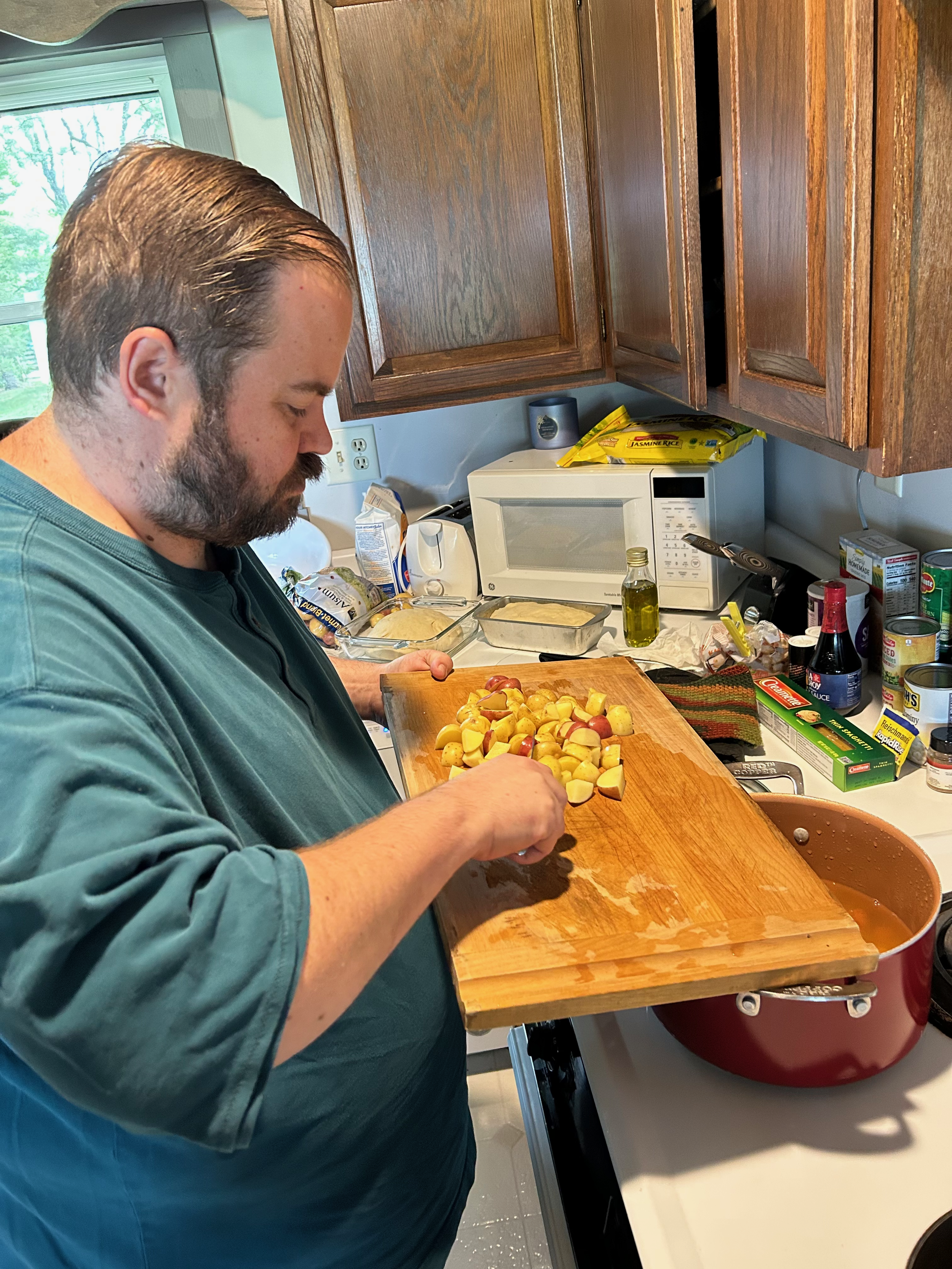 Jesse Rentai, the tenzo during the Minnesota Sesshin, is mindfully scraping some cubed potatoes into a large cooking pot.