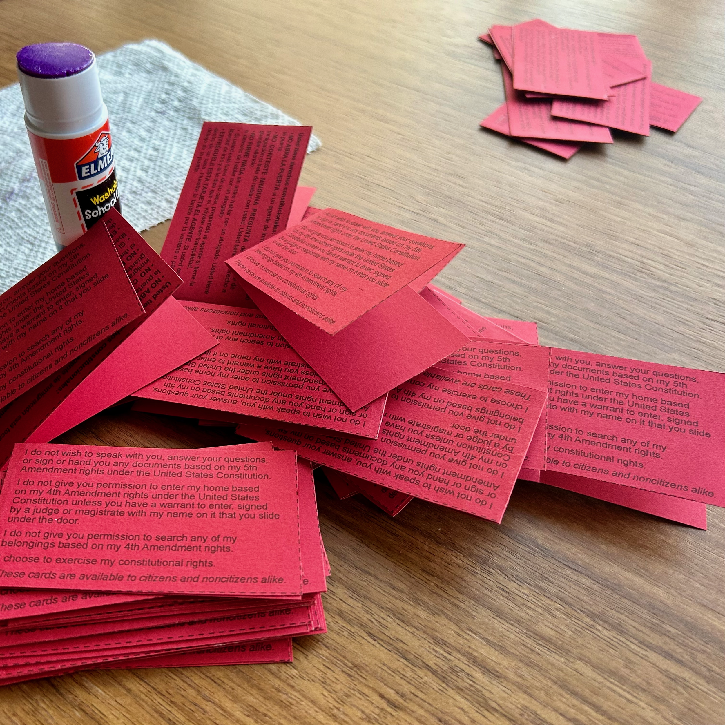 An uncapped glue stick and a pile of red business cards in a variety of languages