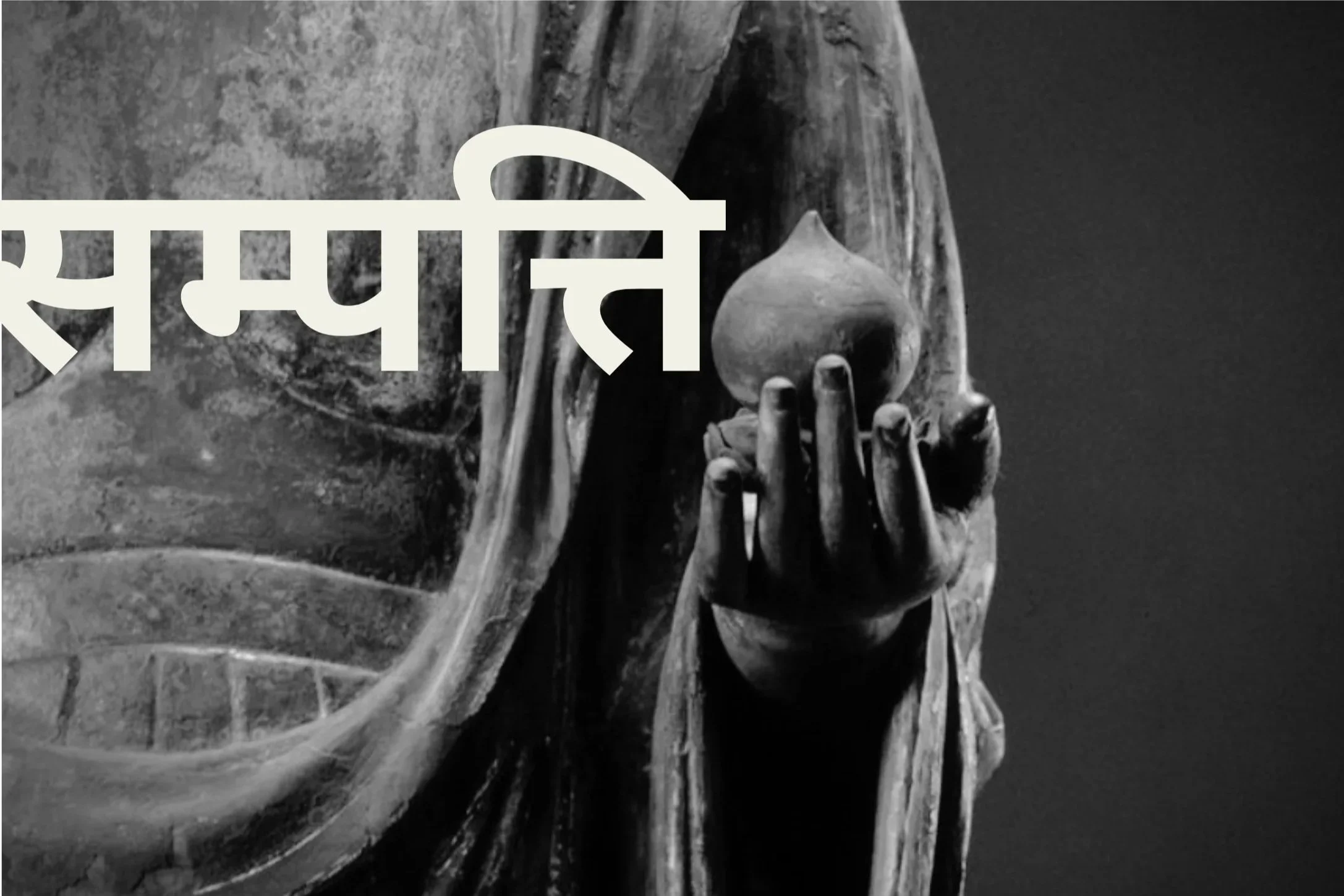 A black and white image of a statue of Jizo Bodhisattva holding a hoju or wish-fulfilling gem with the Sanskrit word Sampatti written in Devanagari script overlayed
