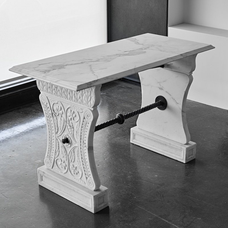 DONATELLO TABLE. Hand carved pedestal legs, braced with hand crafted bronze rail. Solid marble top: 1100 x 600