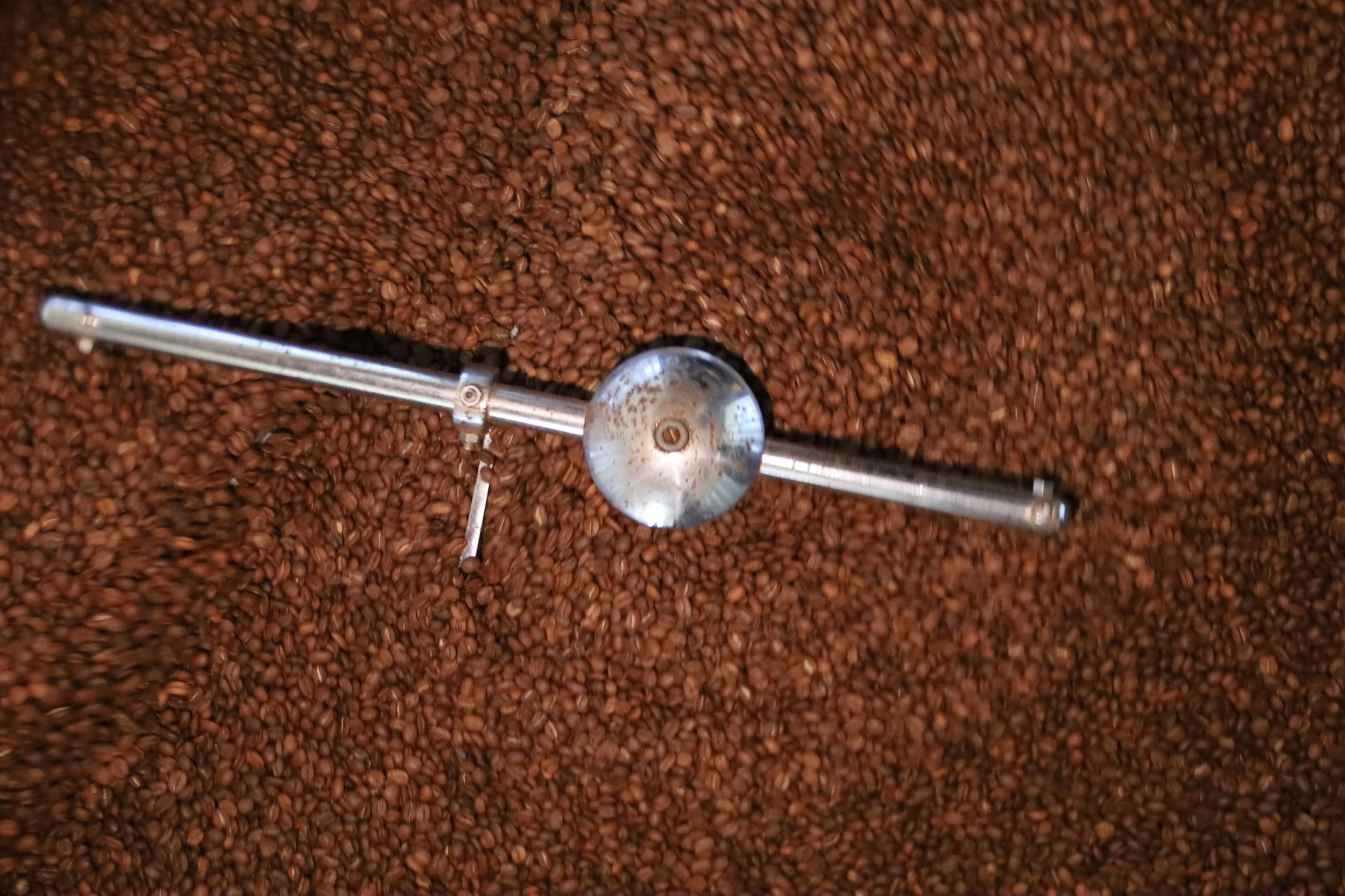 Kompa Nanzi Coffee beans being stirred in a roasting machine.