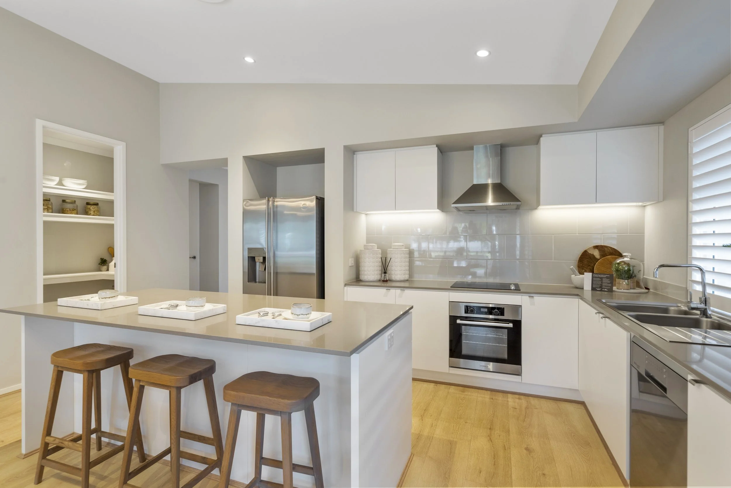Modern U-shaped kitchen with white cabinets, stainless steel appliances, a kitchen island with seating, and hardwood floors.