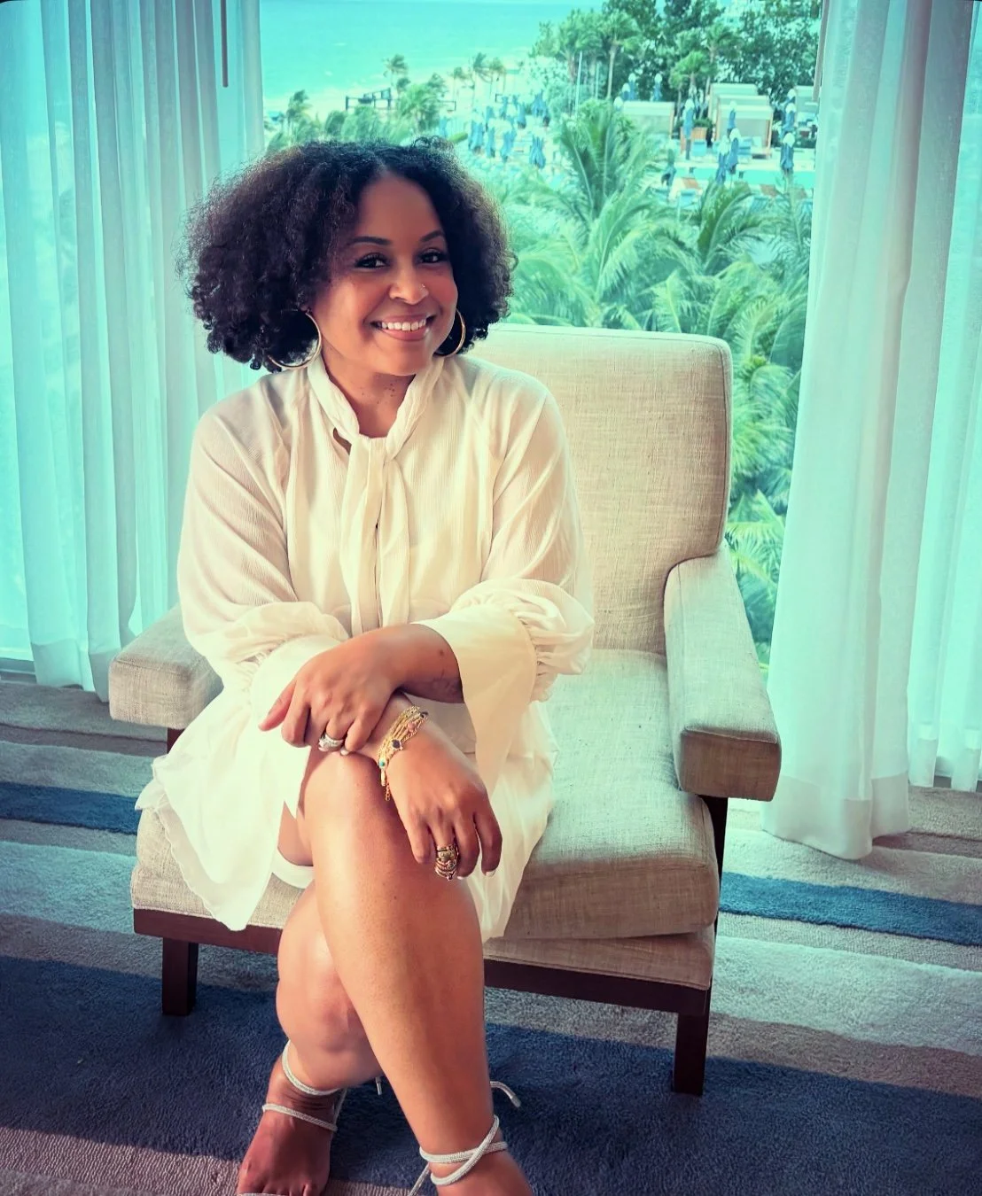A woman seated with legs crossed with curly hair
