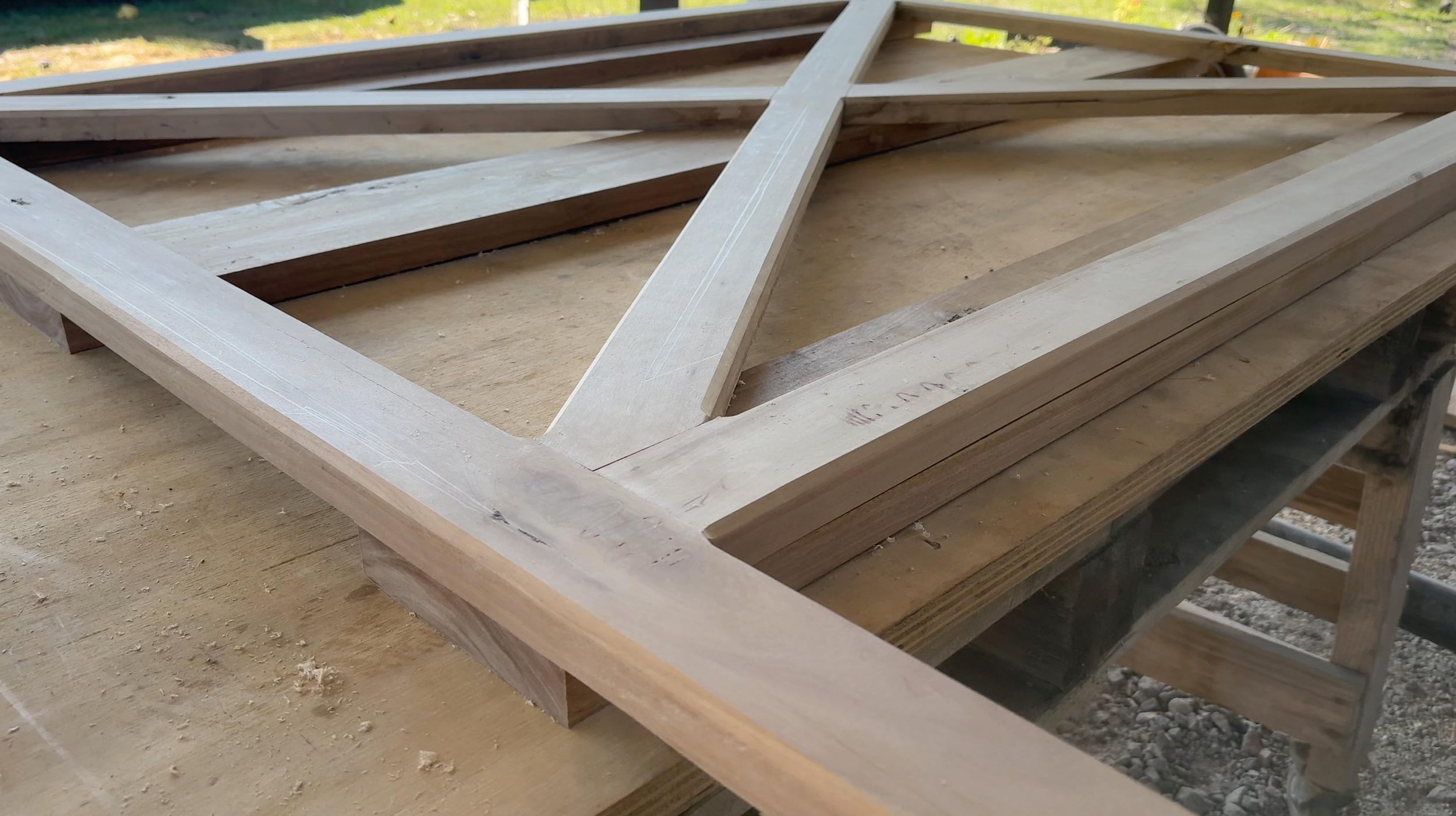A wooden framework for a construction project on a workbench, with lumber and construction materials nearby.