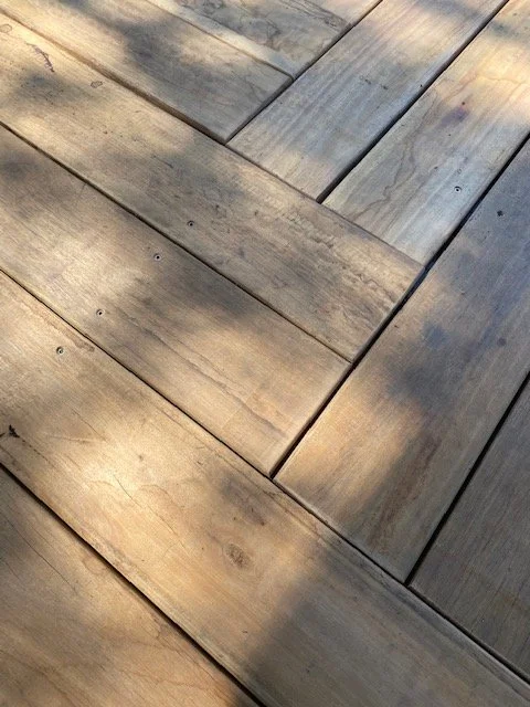 Close-up of a wooden deck with weathered planks arranged in a perpendicular pattern.