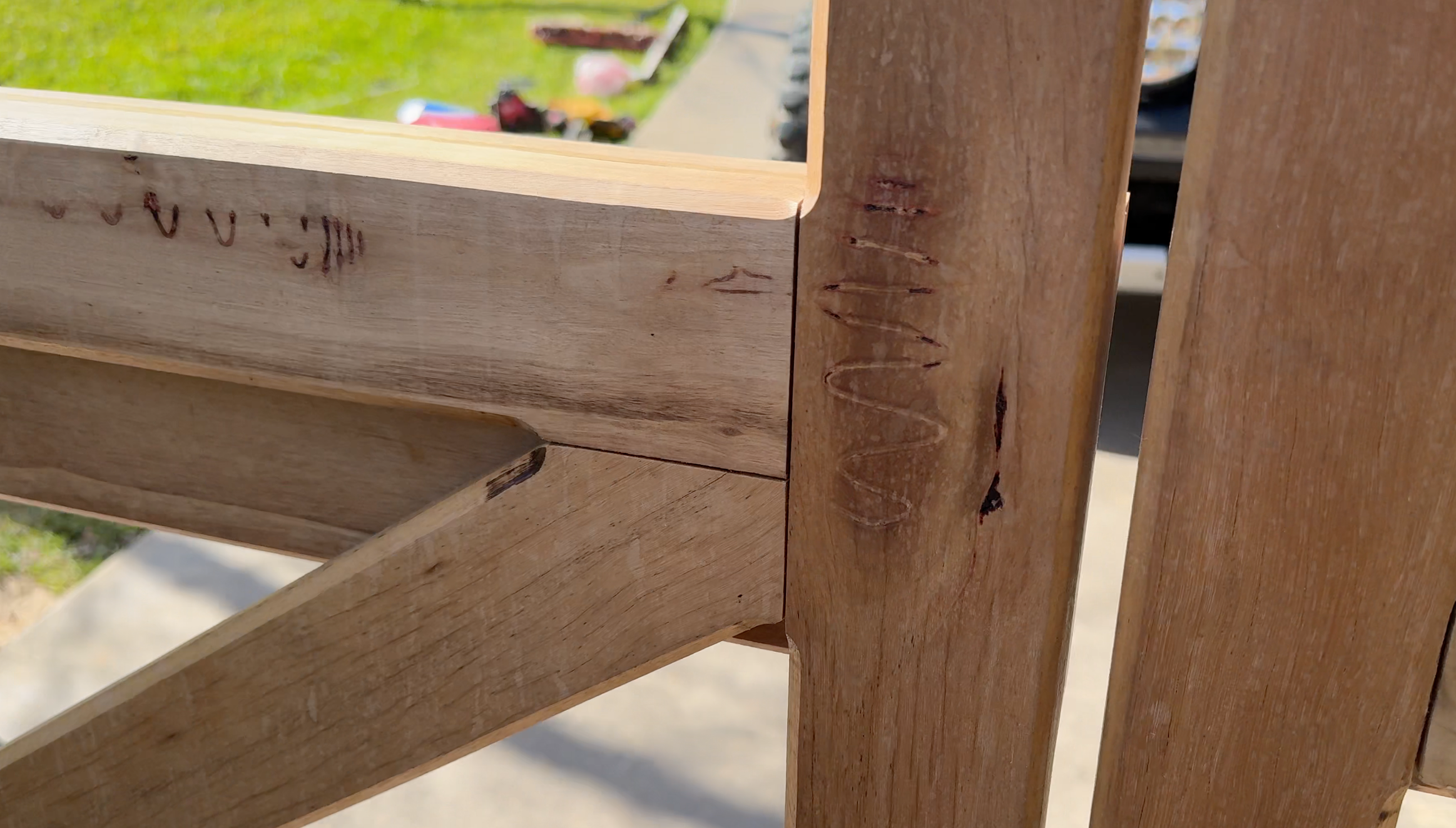 Close-up of a wooden structure, showing detailed wood grain and craftsmanship, with a blurred outdoor background.