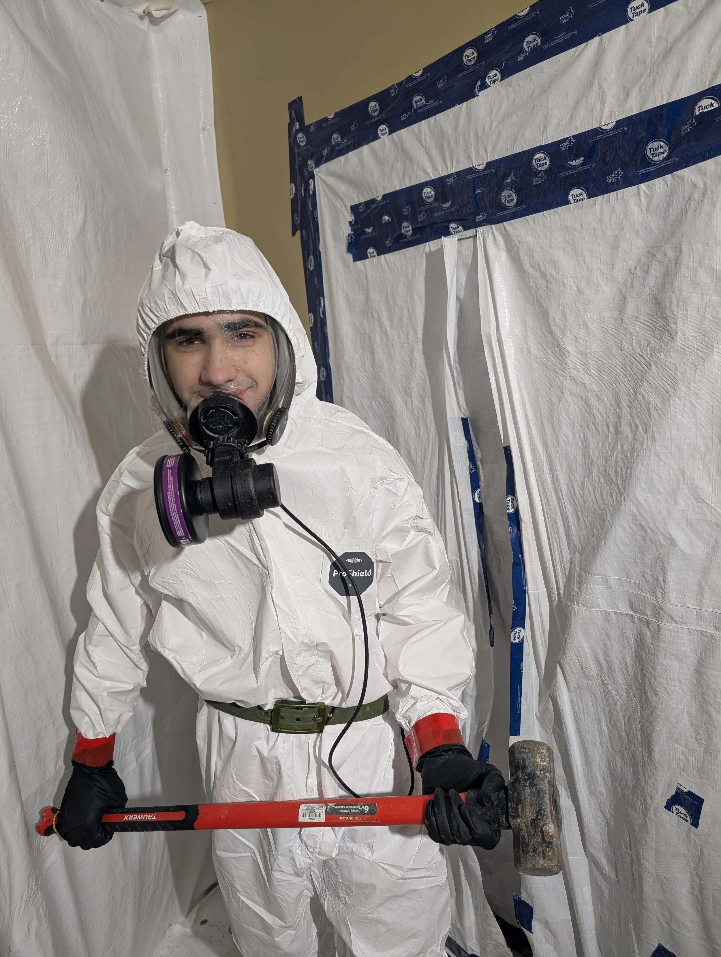 An Interior Abatement technician wearing full WorkSafeBC-mandated PPE, including a Tyvek suit and P100 respirator, for safe asbestos removal in the Okanagan.