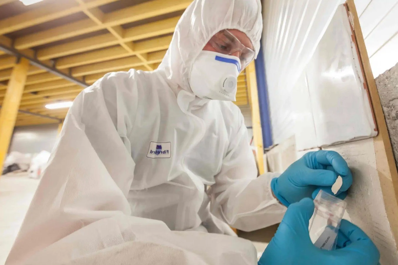 Certified technician taking a drywall sample for professional asbestos testing in a Vernon residential home.