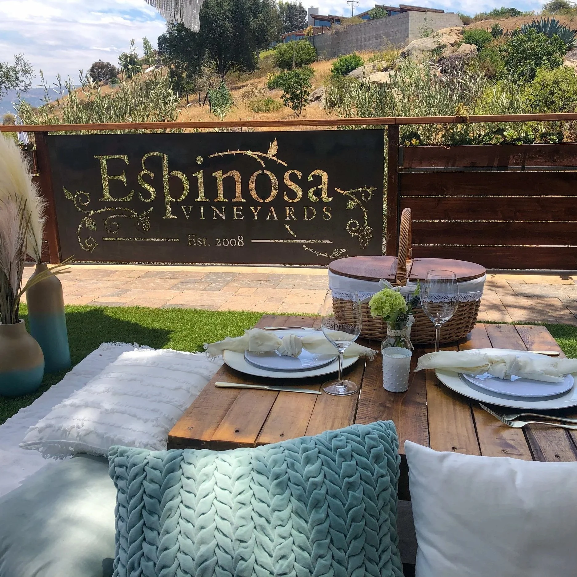 round table on a beach with a sheer table cloth, rose champagne, surrounded by roses in the ground and a neon sign that says will you marry me