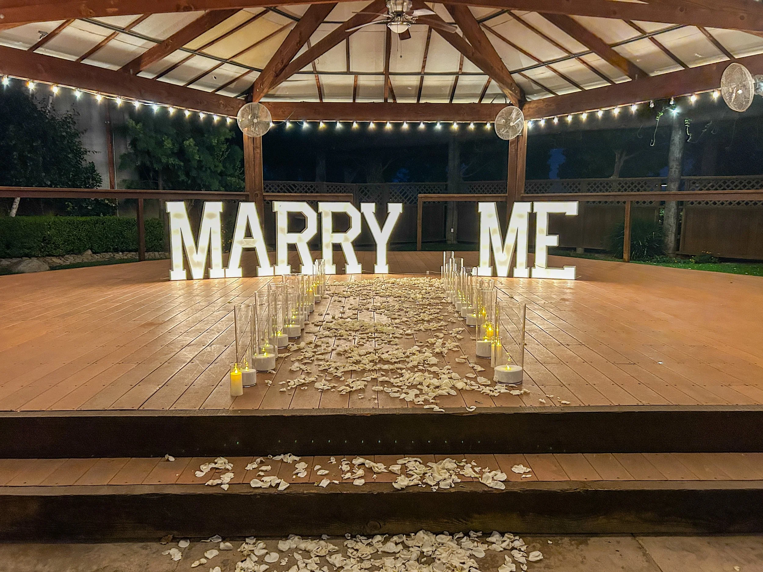 Marry Me marquee sign with candlelight and rose petals