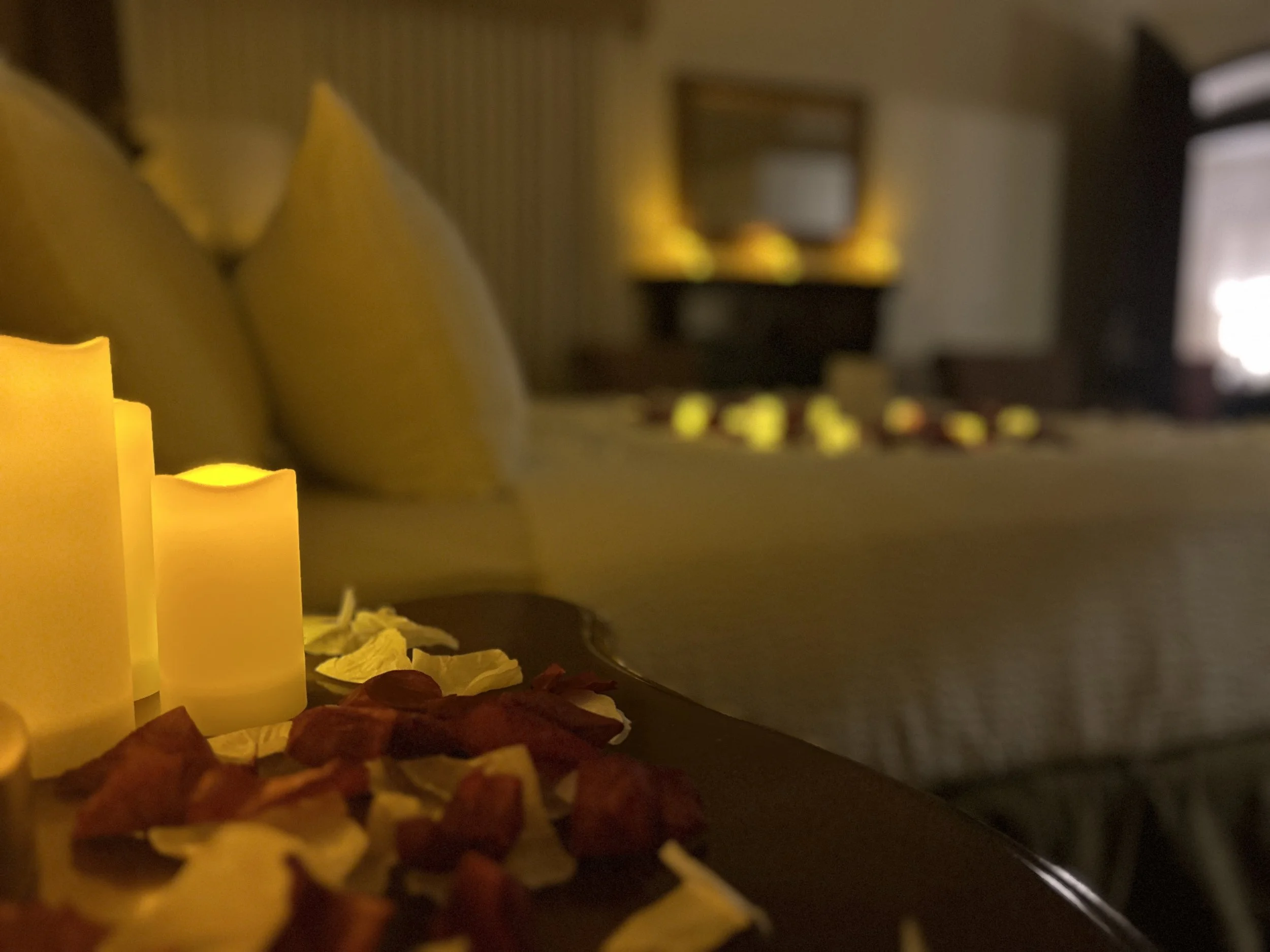 a floor covererd with rose petals and tealight candles leading to a bedroom