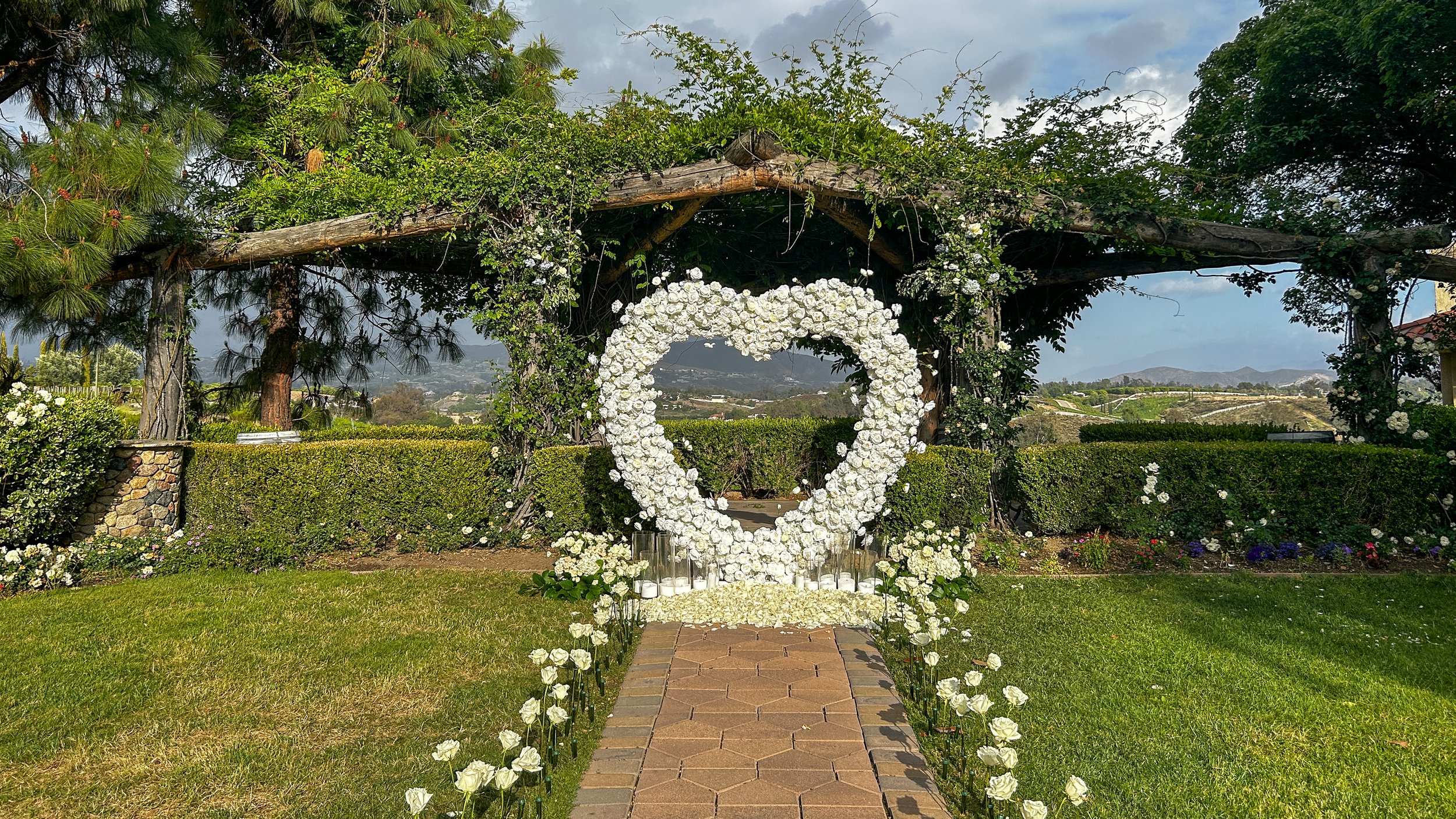 heart arch candle light and rose proposal in front of a rose arbor overlooking vineyards