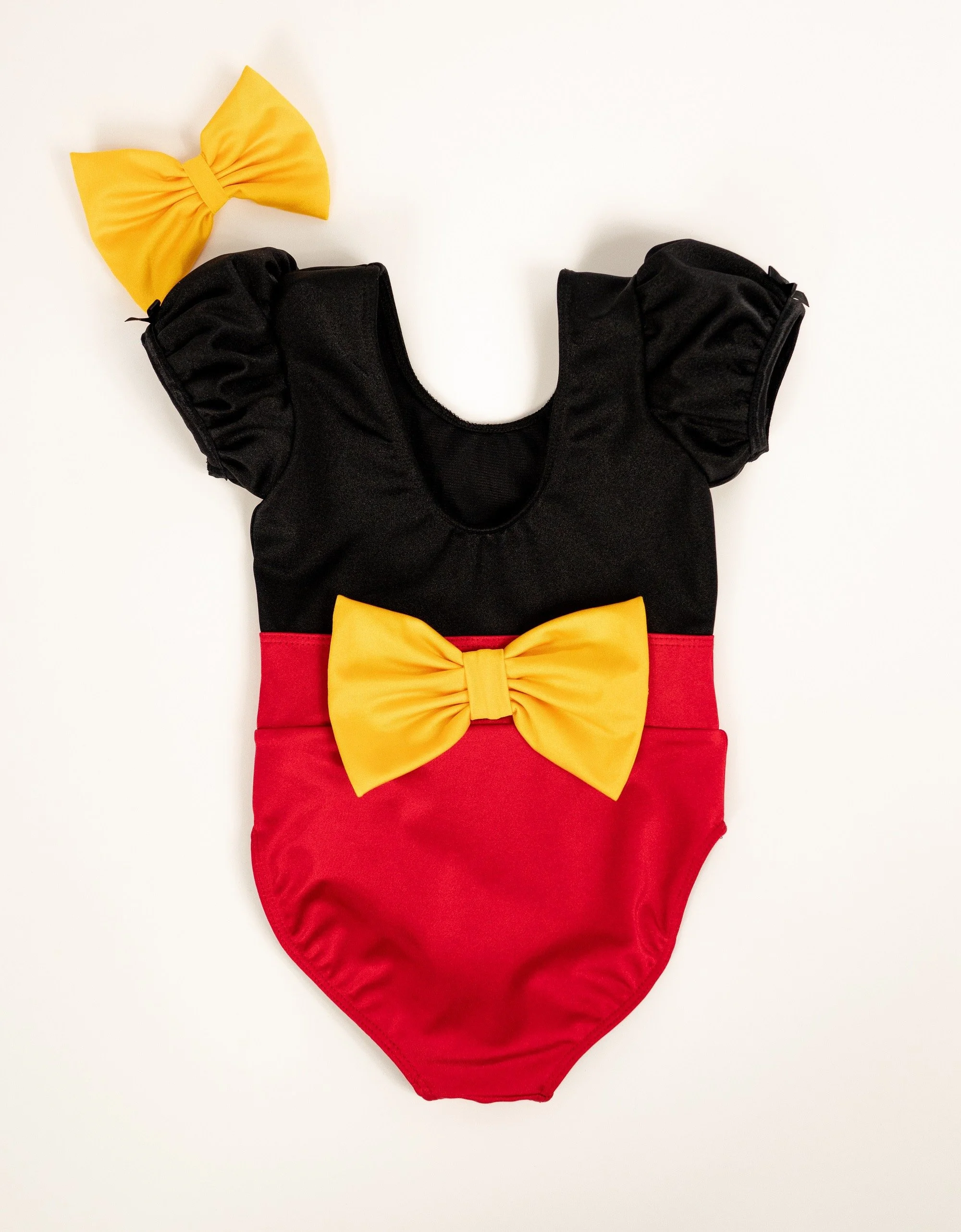 A black and red baby onesie with yellow bow ties—one on the chest and one on the shoulder.