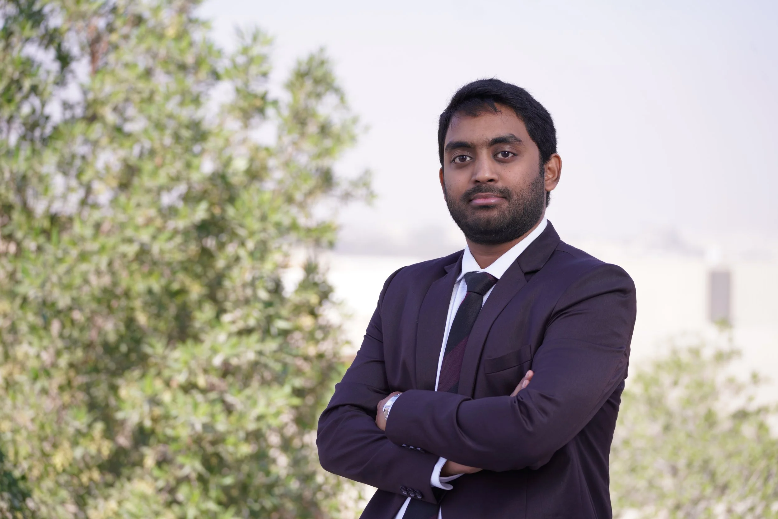 Man in a burgundy blazer standing in front of a backdrop with cursive and block lettering.
