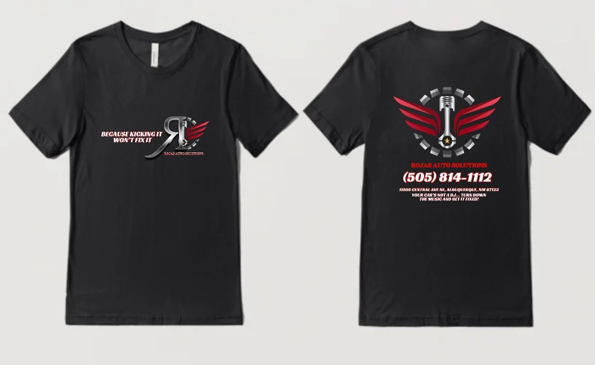 Black T-shirt with a logo on the front and back. The front logo features a stylized R with a piston and red wings, with the text "BECAUSE KICKING IT WON'T FIX IT" and "ROJAS AUTO SOLUTIONS". The back has a large red and black winged piston logo, the 