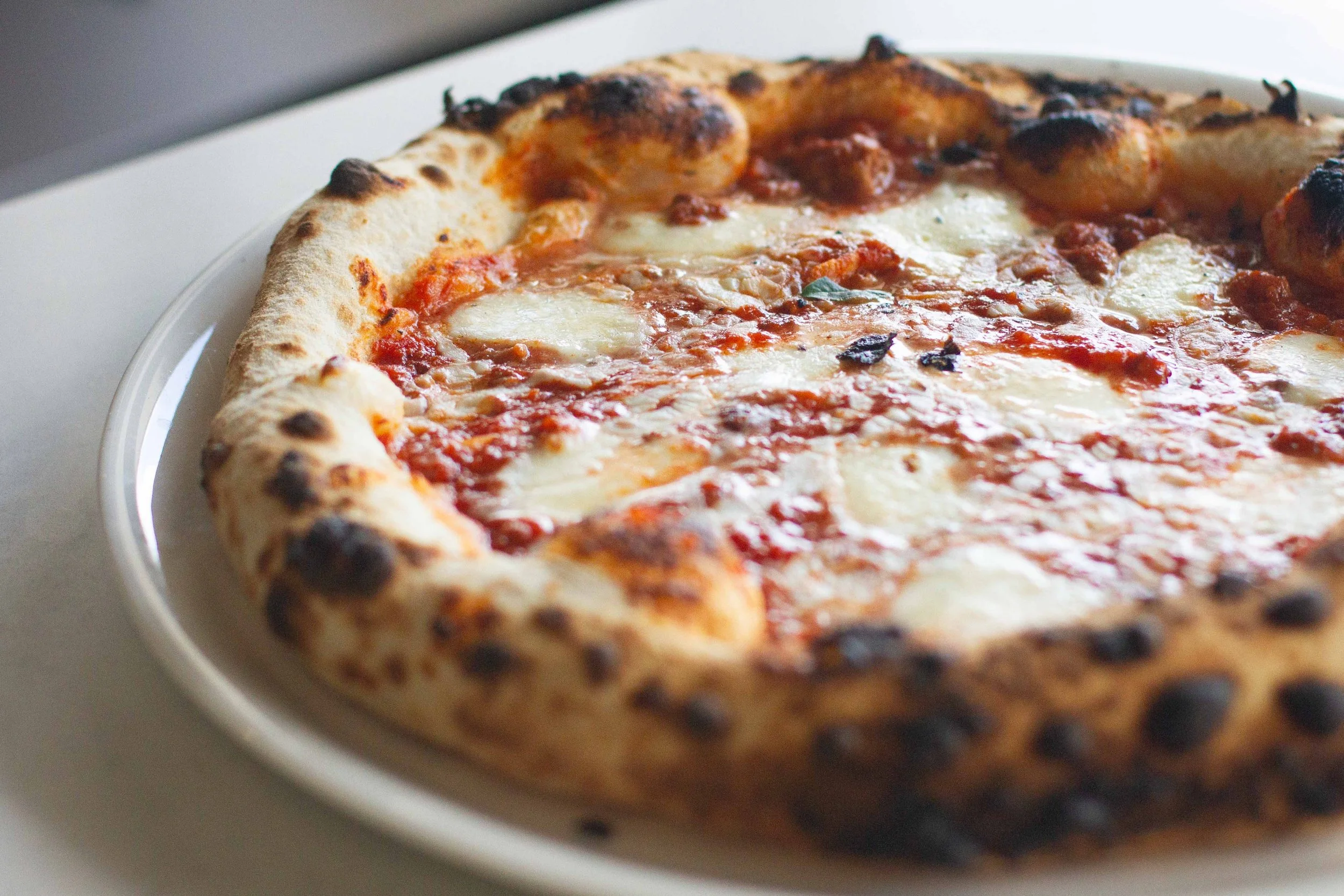 Close-up of a cooked pepperoni pizza with melted cheese on a white plate.