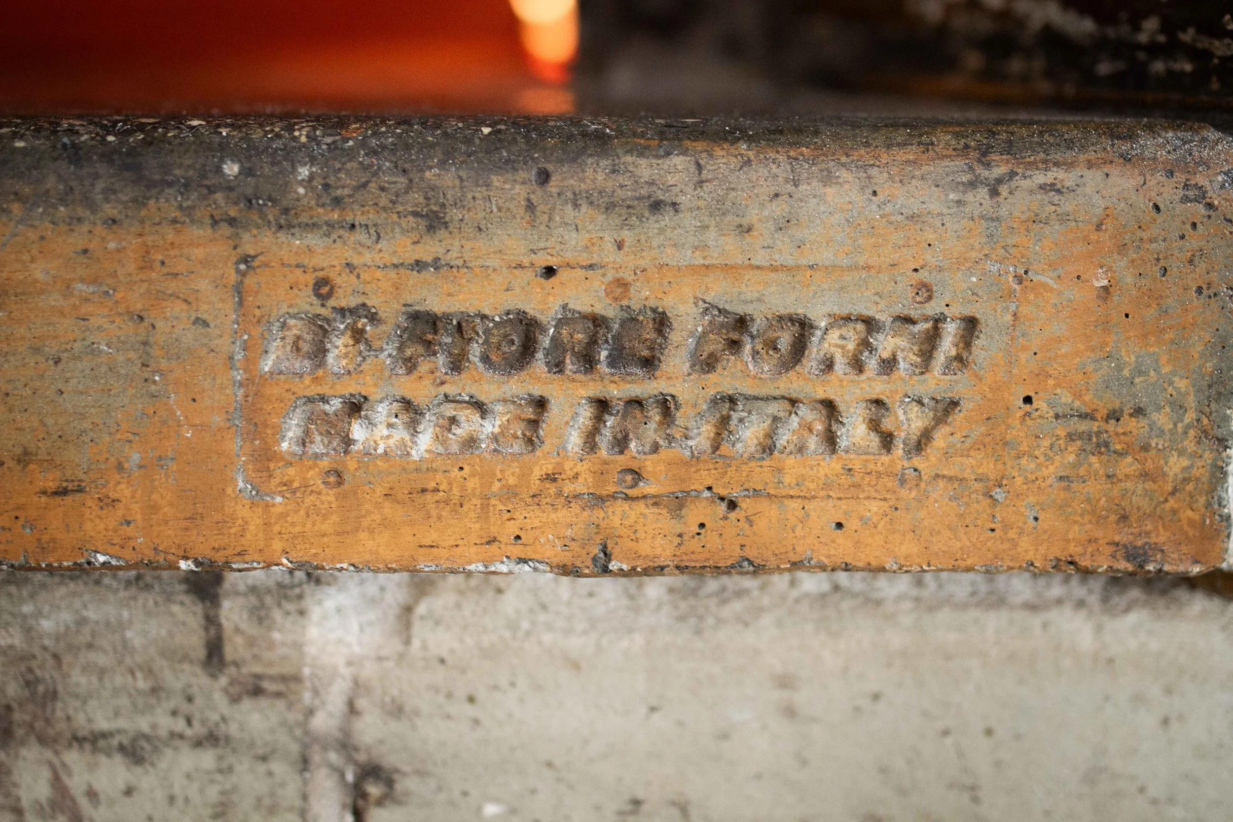Close-up of a brick with embossed text that reads 'D&M COLLI MADE IN ITALY'.