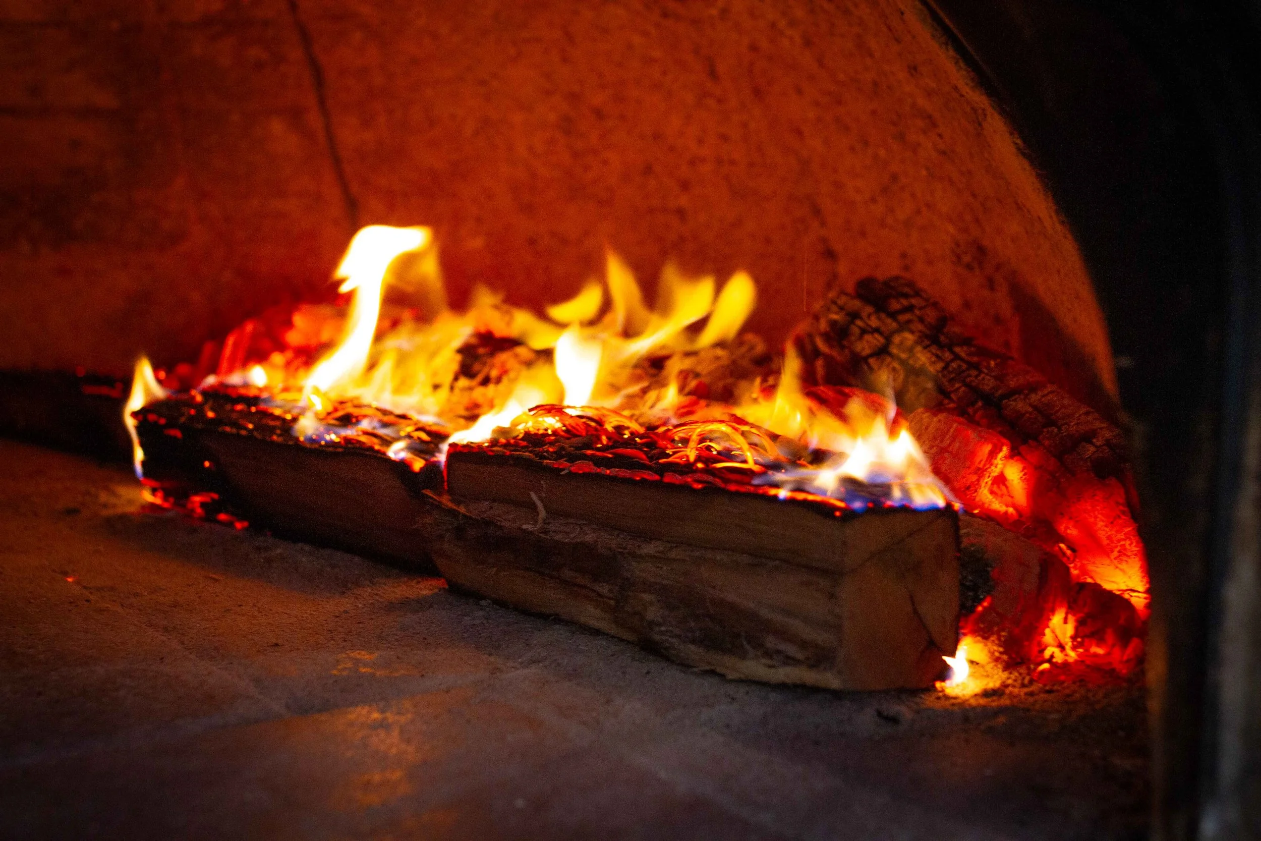 Burning logs inside a fireplace with visible flames and glowing embers.