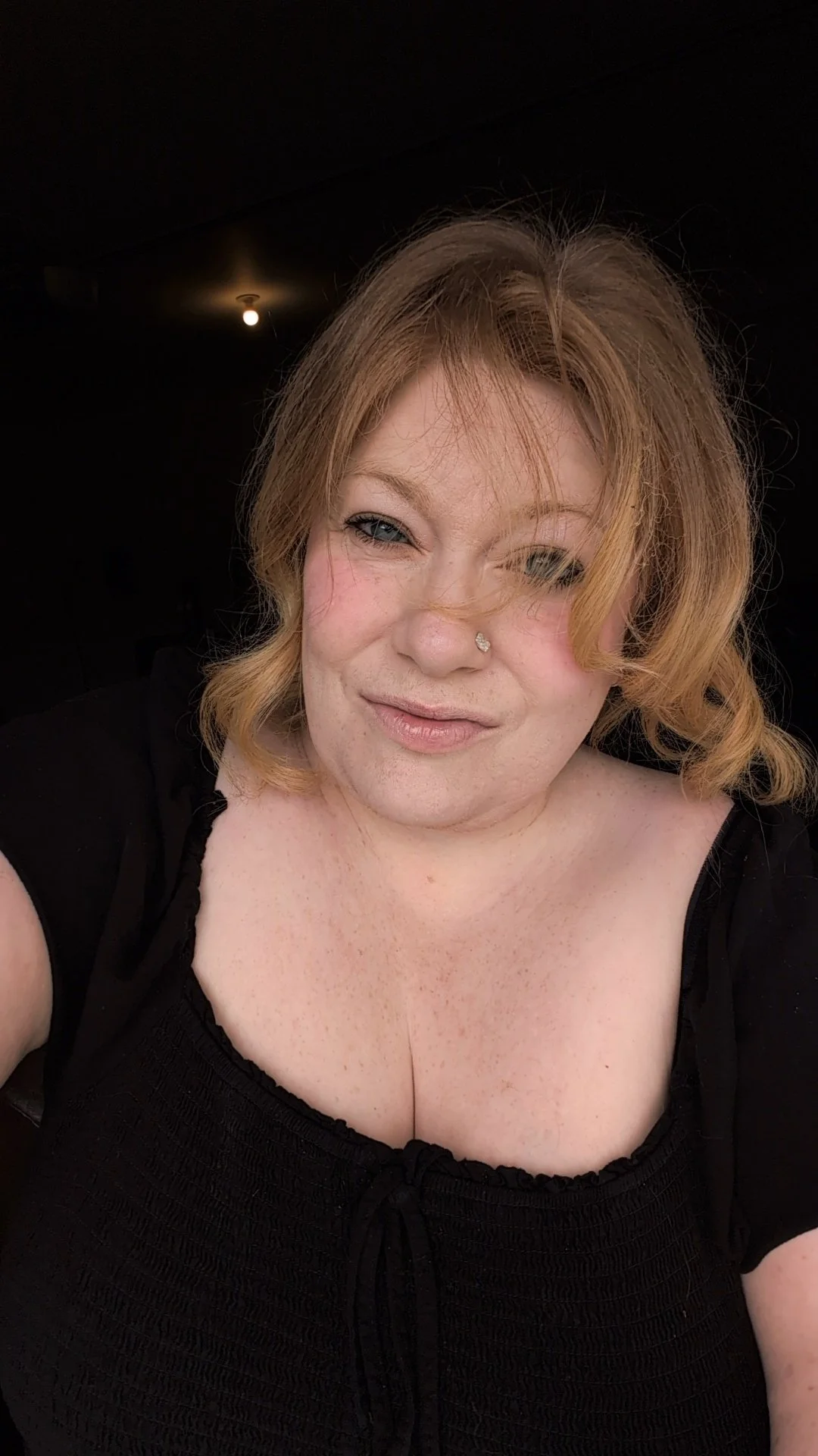 redhead standing in a doorway with black shirt on and a light behind her.