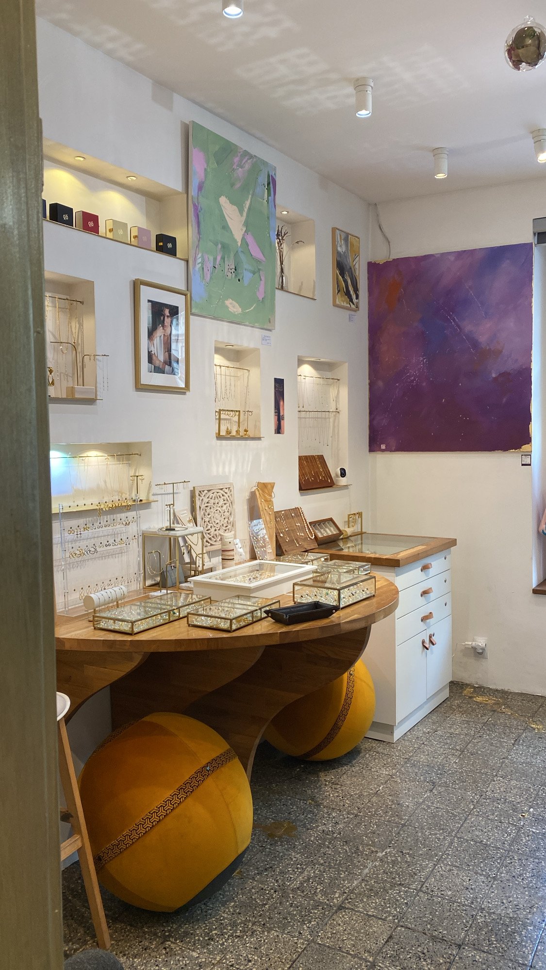 Interior of a jewelry shop and art gallery with wall art and jewelry on shelves.