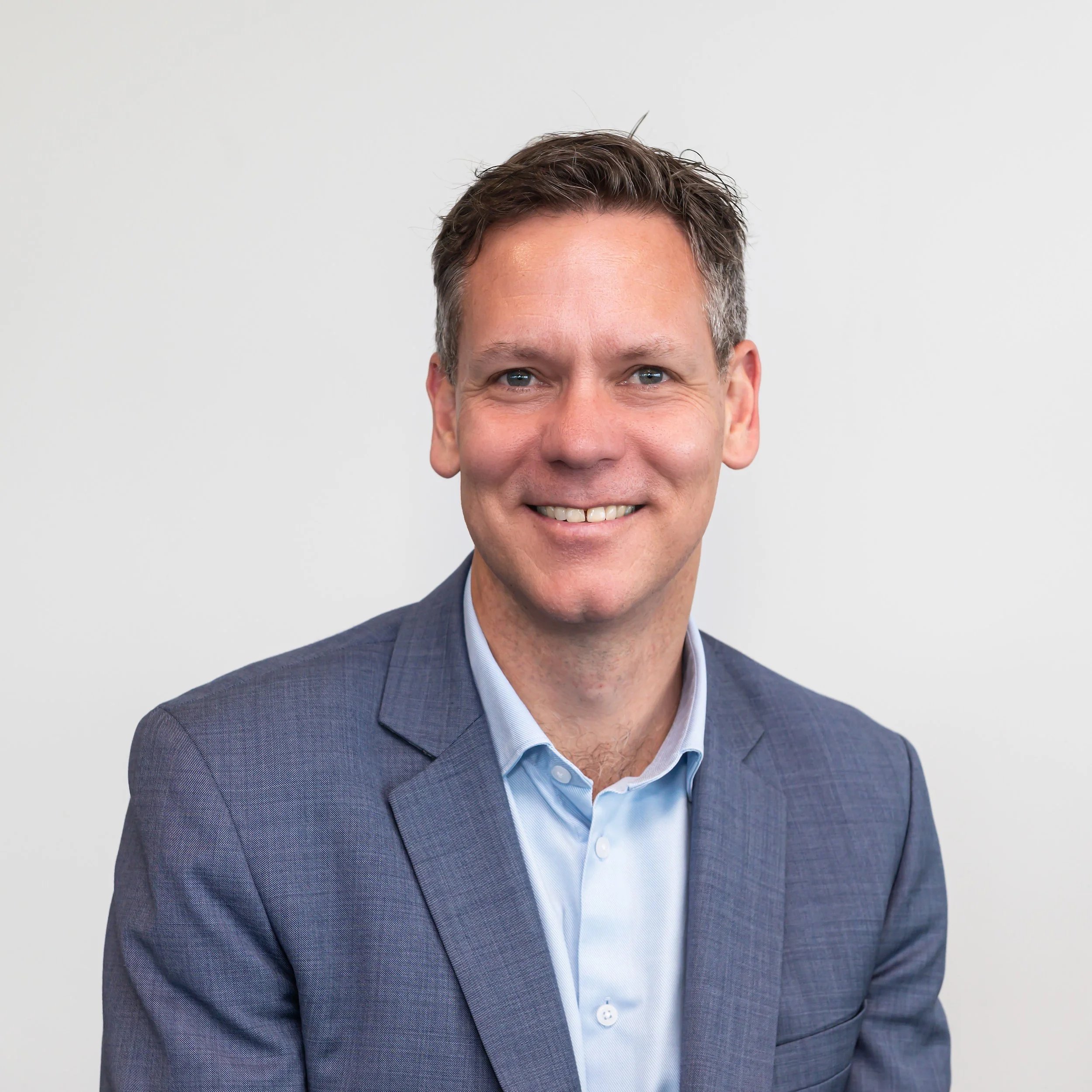 Smiling man in blue suit and shirt against white background