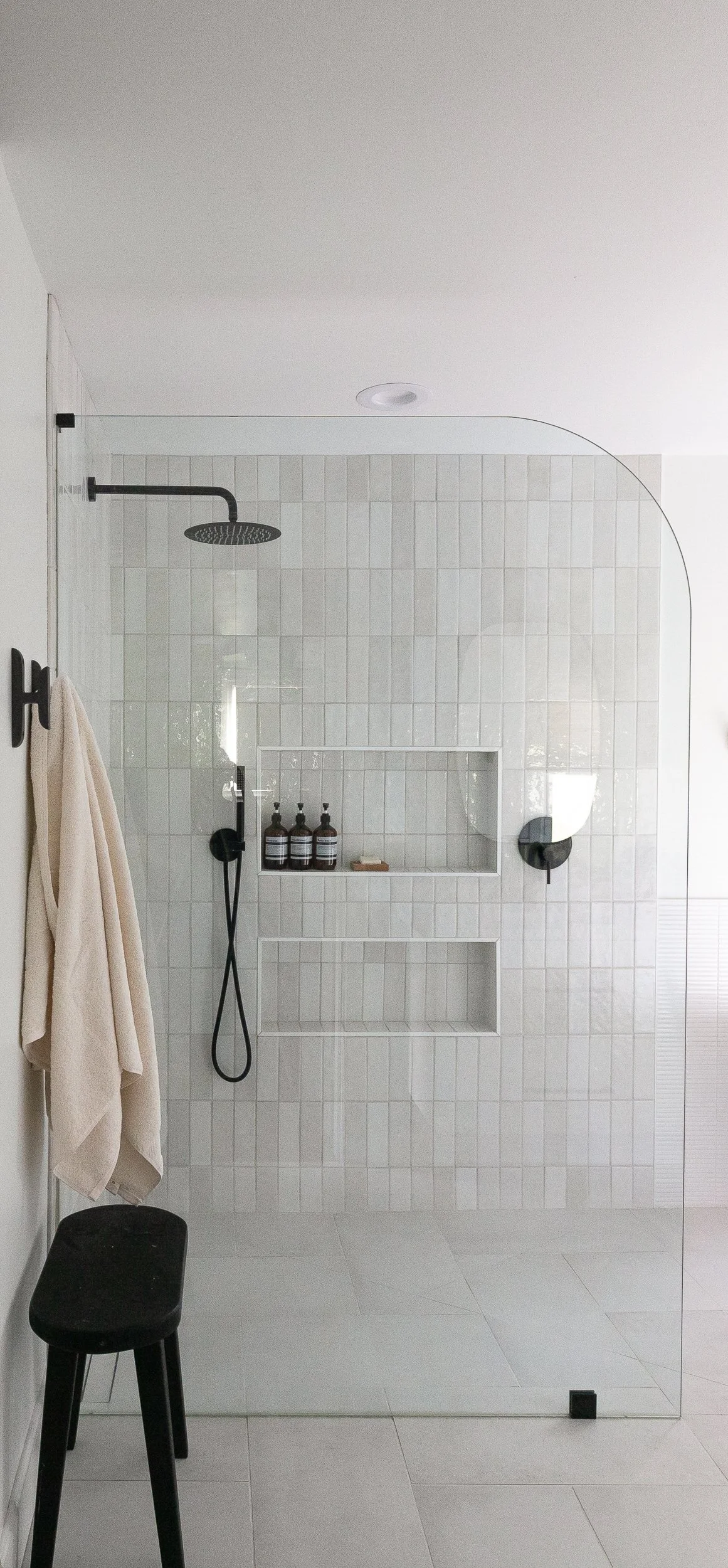 Modern walk-in shower with white tile and black fixtures in a Cincinnati bathroom renovation