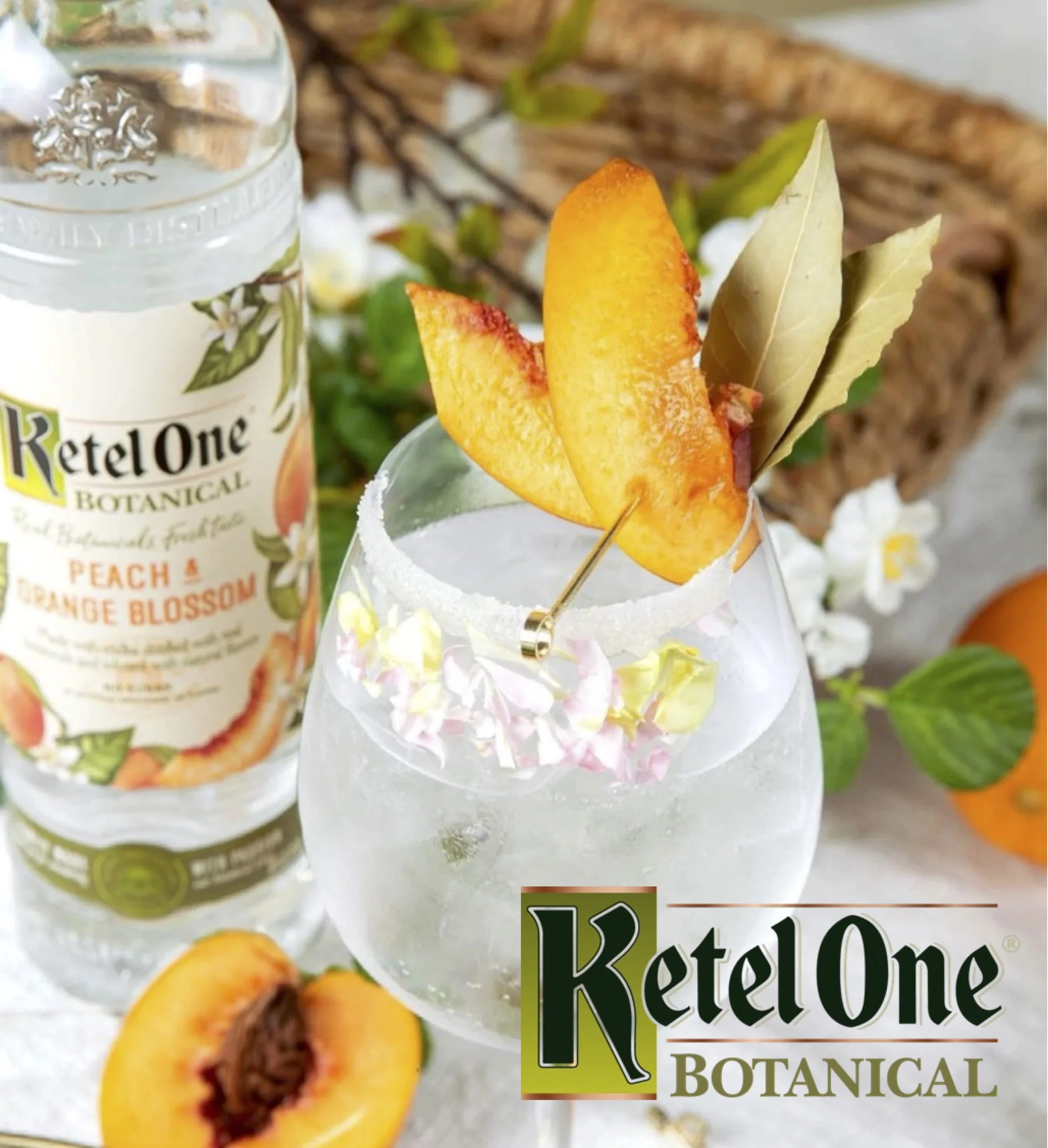 Three bottles of Ketel One Botanical flavored spirit drinks with glasses of cocktails garnished with fruit slices on a wooden table.