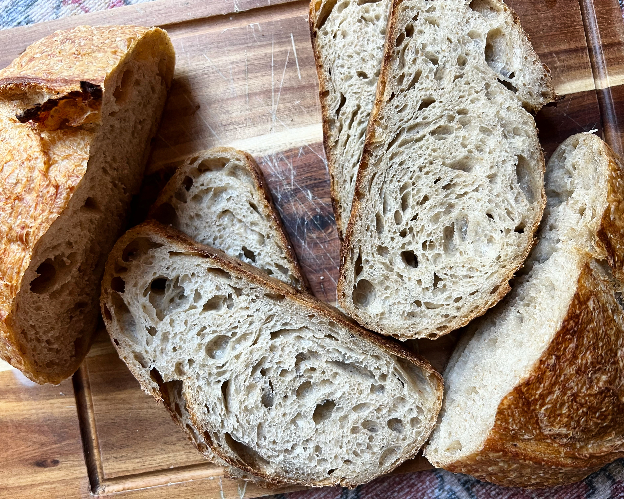 Slices of freshly baked rustic bread on a wooden cutting board.